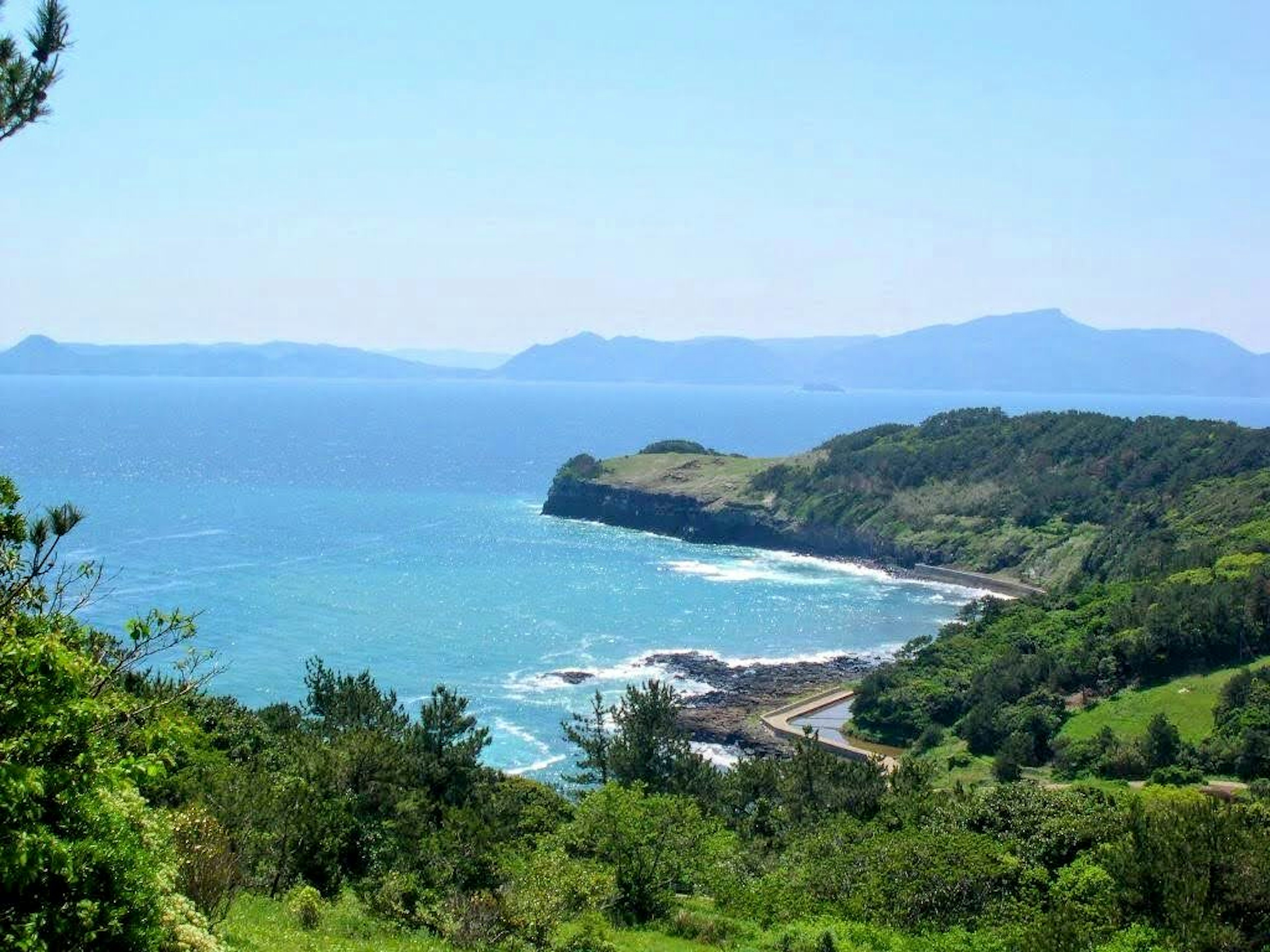 Vue panoramique d'une mer bleue et de collines verdoyantes côte visible