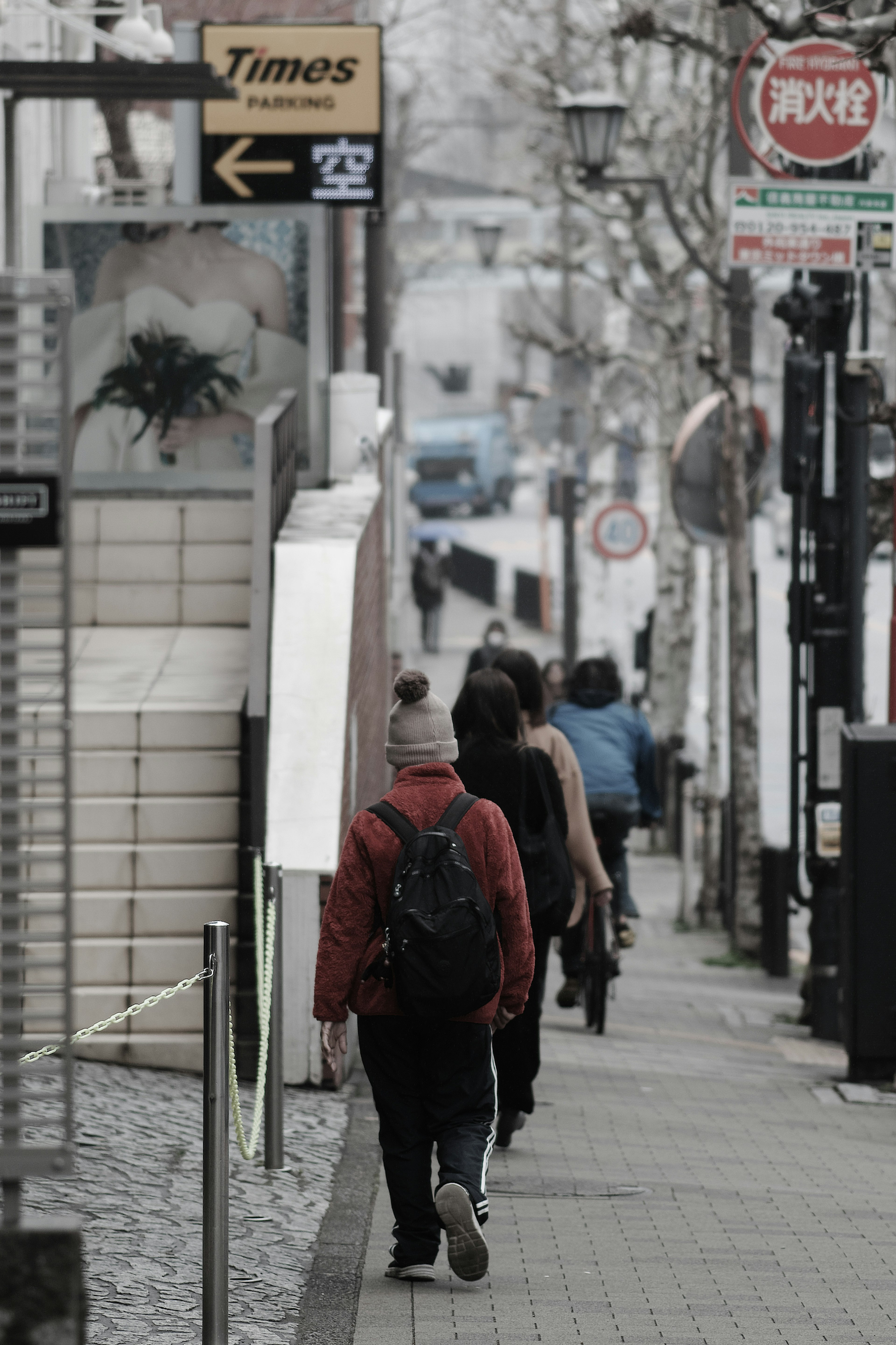 Personas caminando por una calle de la ciudad con una figura vestida de rojo y señalización visible