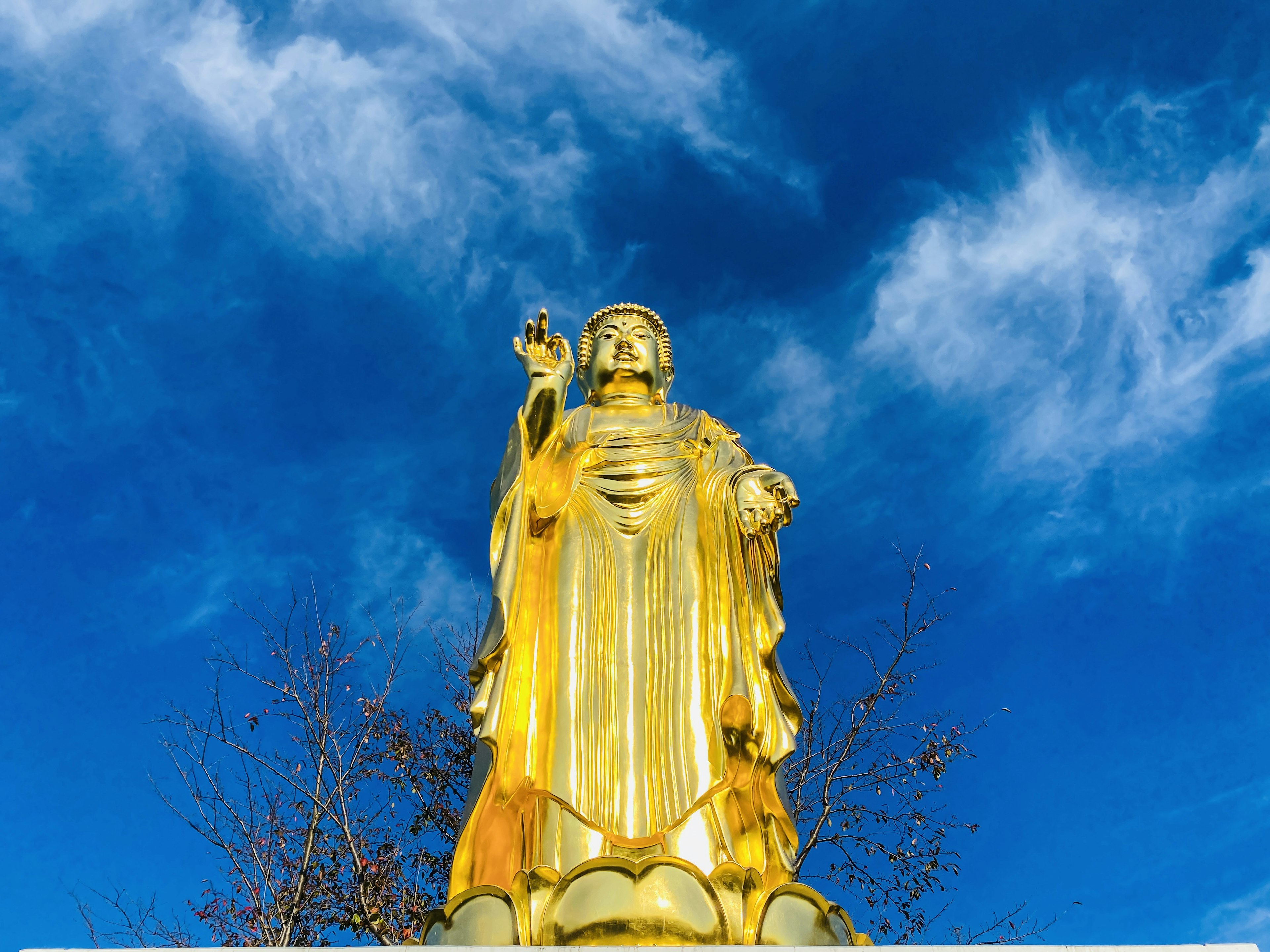 Vista completa de una estatua dorada de Guanyin bajo un cielo azul