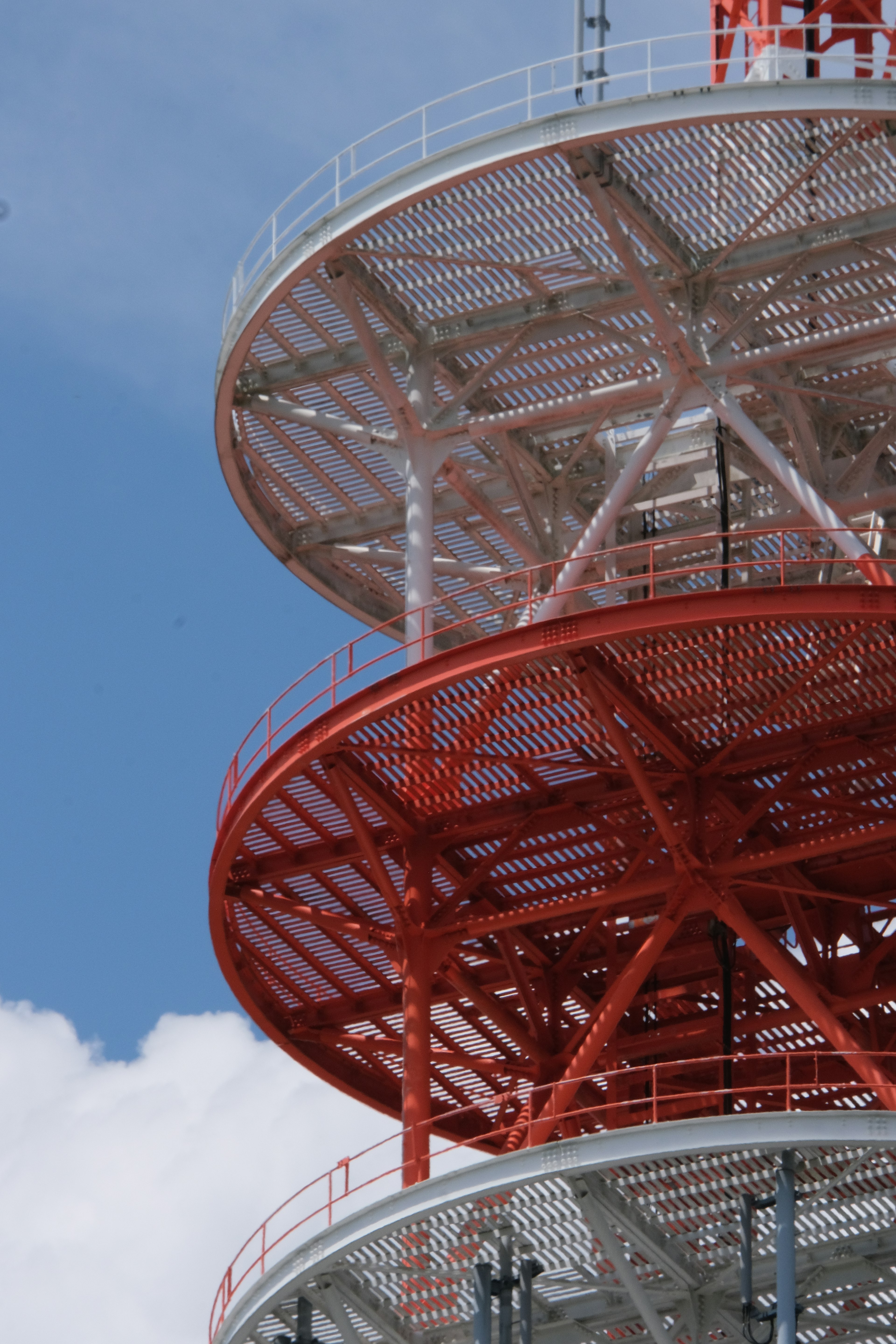 Structural details of a red and white communication tower against a blue sky