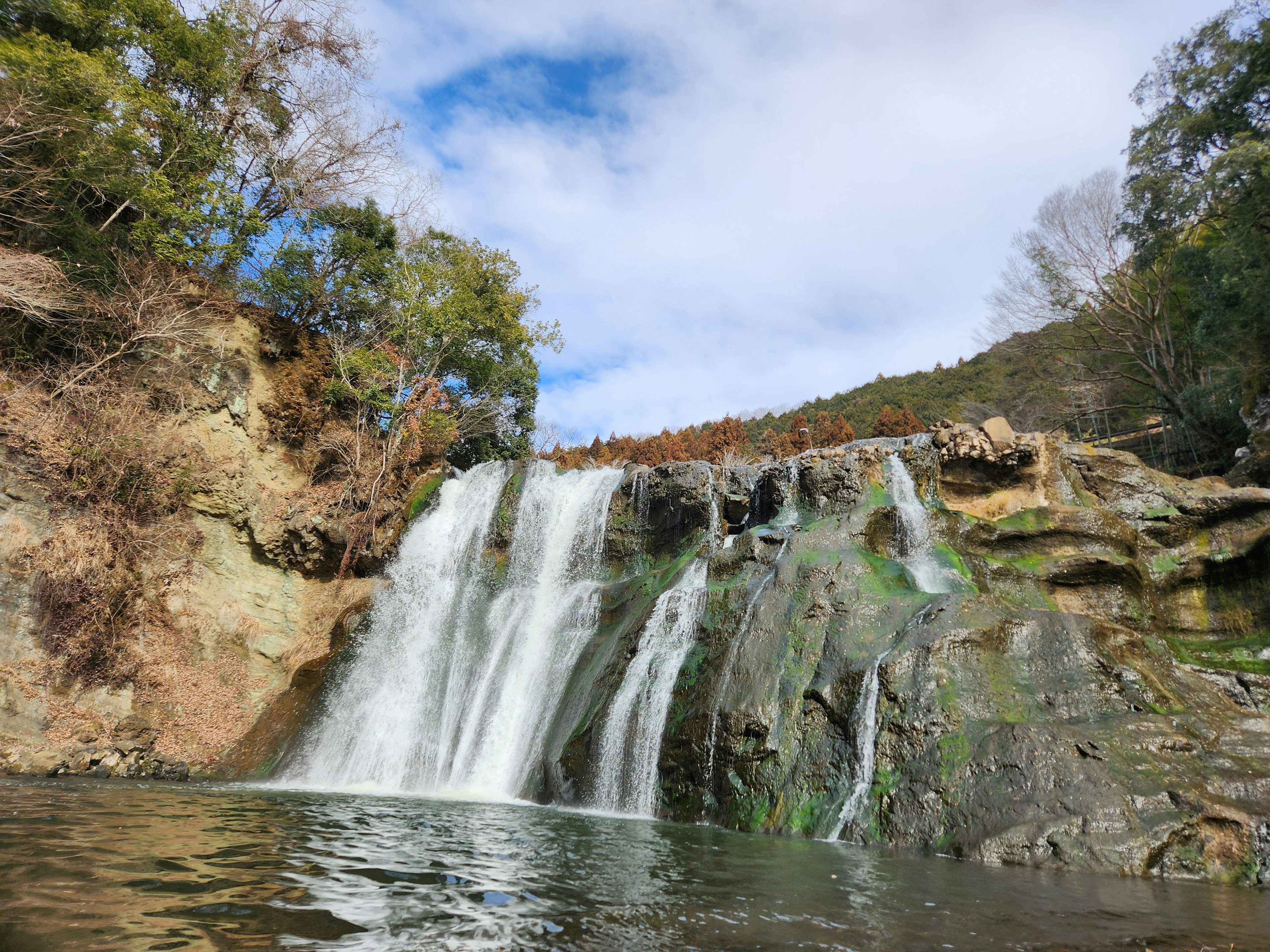 Belle cascade d'eau tombant sur des rochers avec une surface d'eau sereine