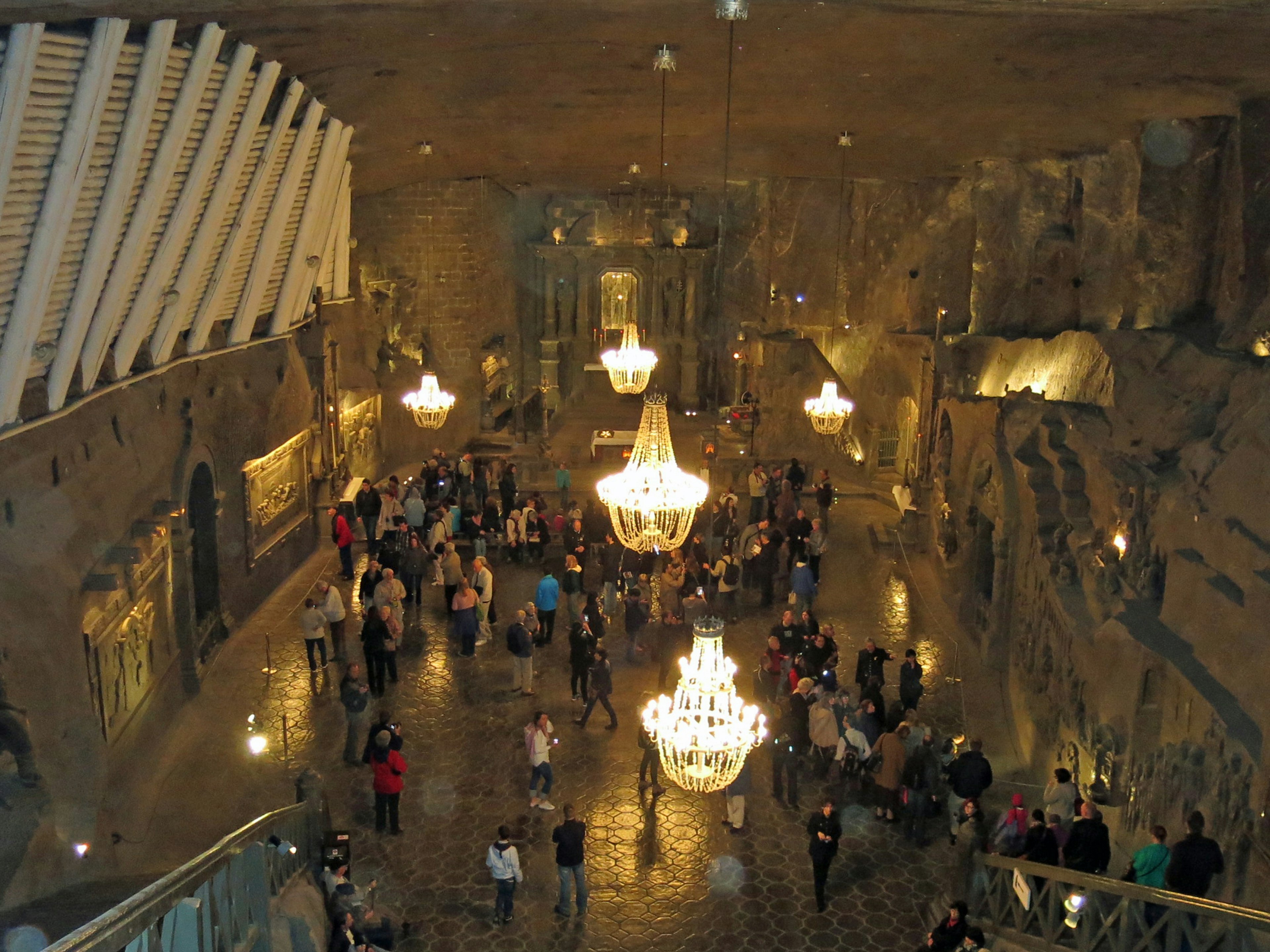 Un grand hall souterrain rempli de personnes avec des magnifiques lustres suspendus au plafond