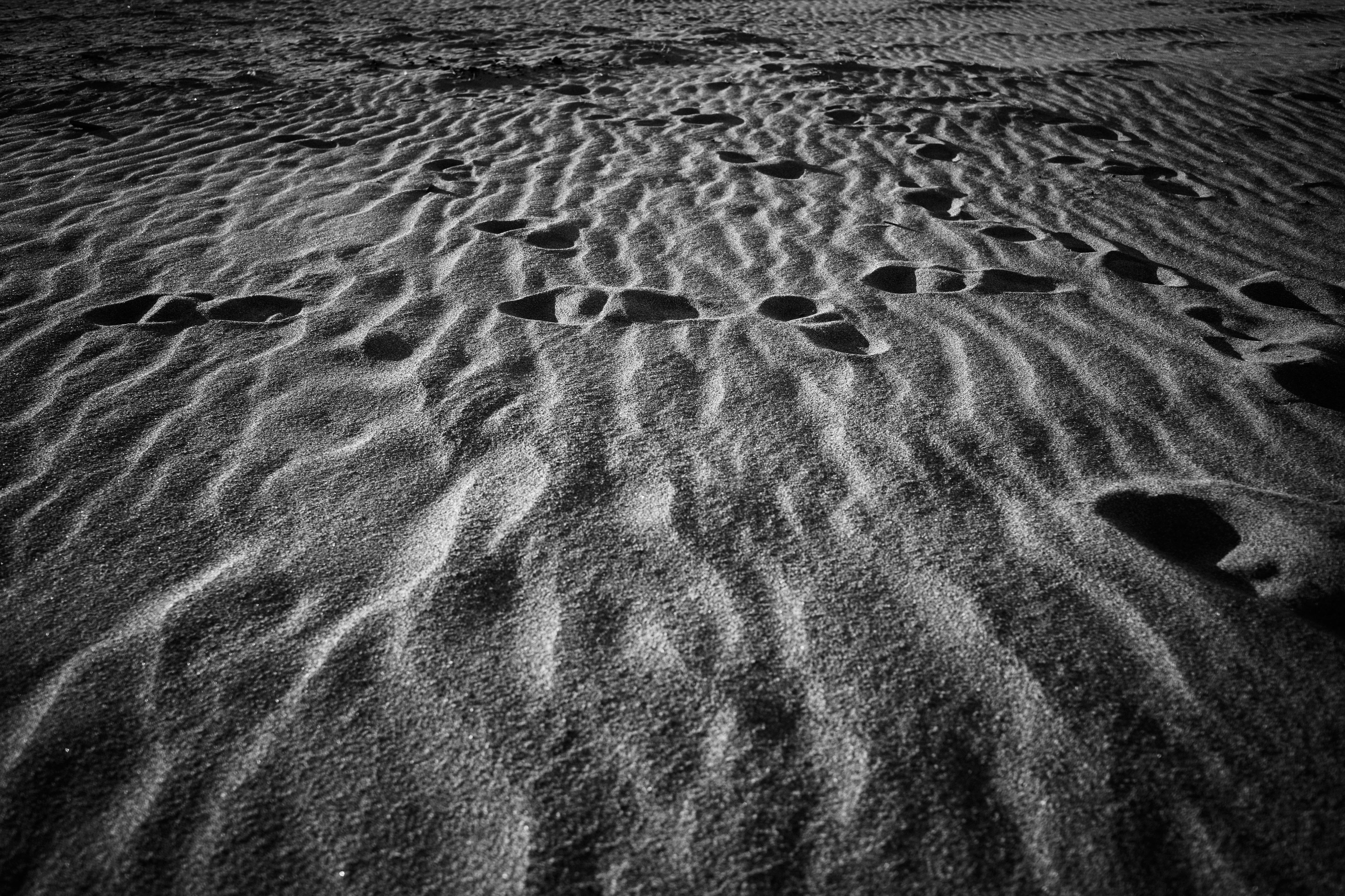 Fußabdrücke und gewellte Muster im Sand