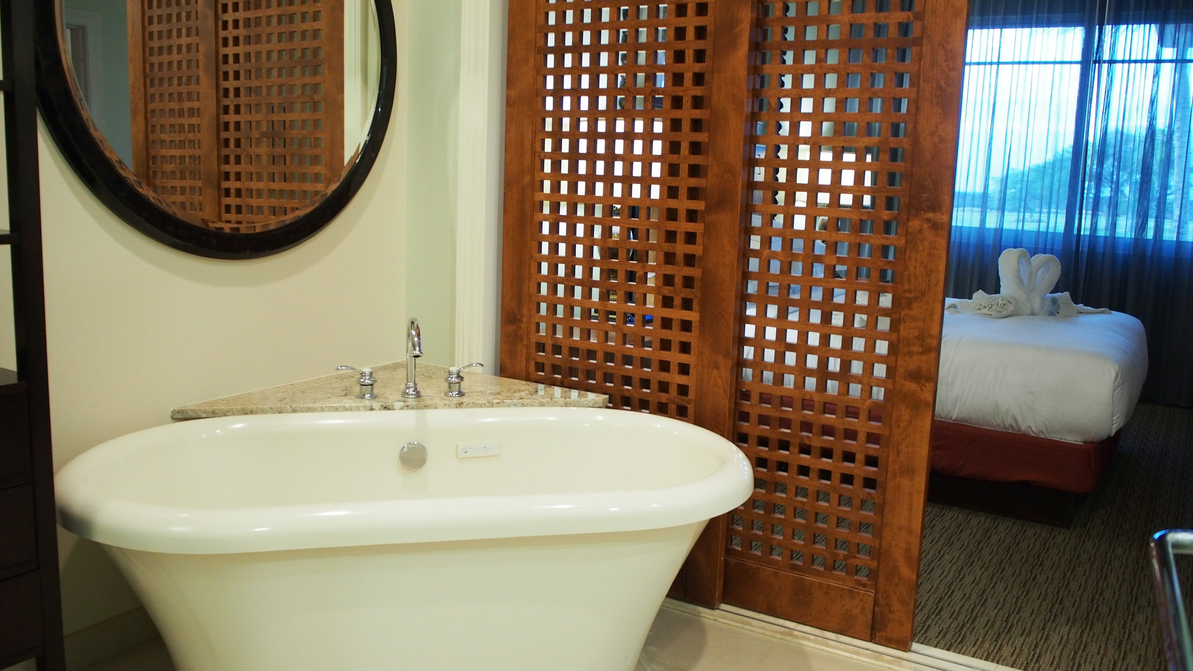 Salle de bain avec baignoire blanche près d'un lavabo et une cloison en bois