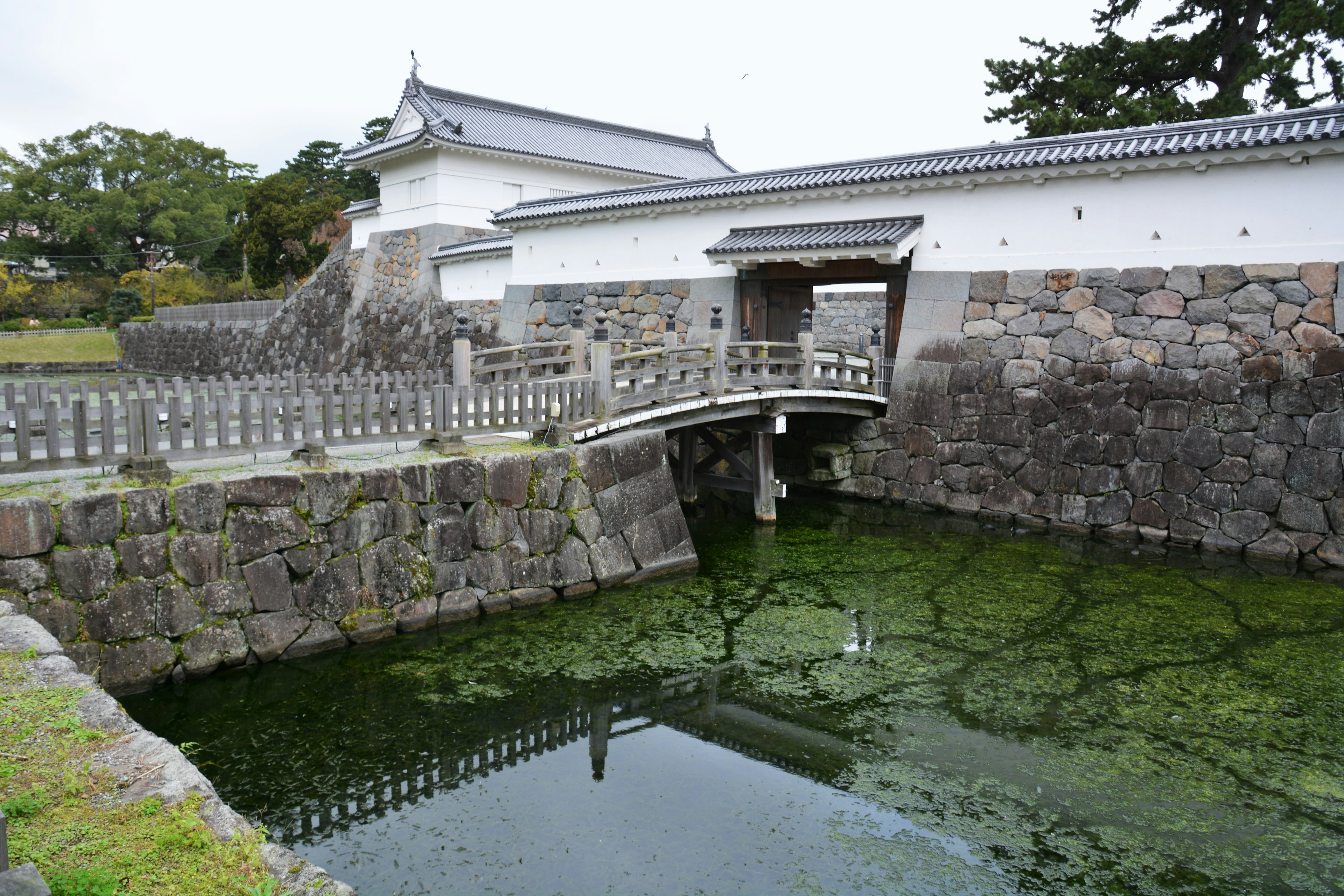 Entrada de castillo japonés con puente de piedra y estanque