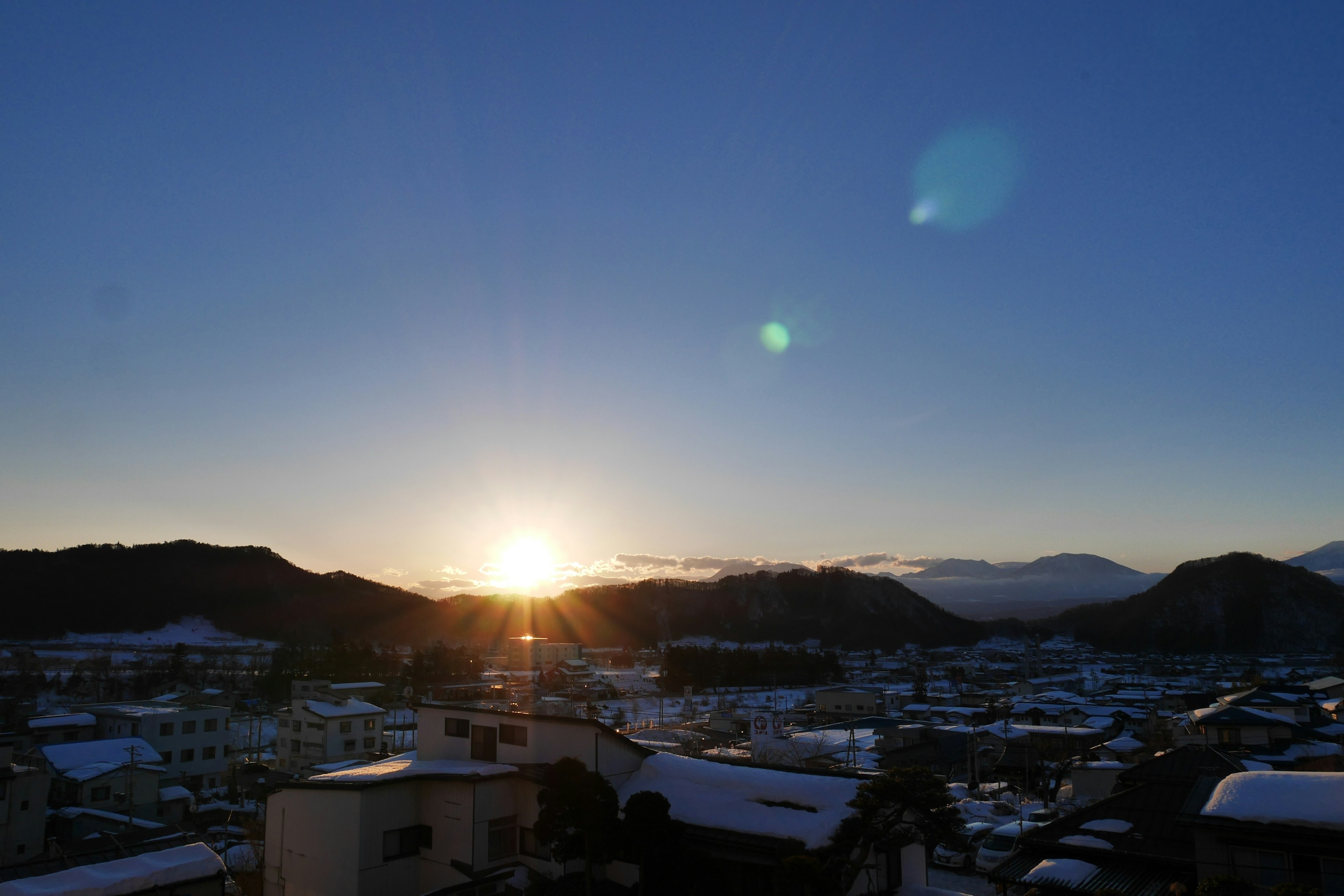 Vue magnifique du soleil se levant sur une ville enneigée et des montagnes