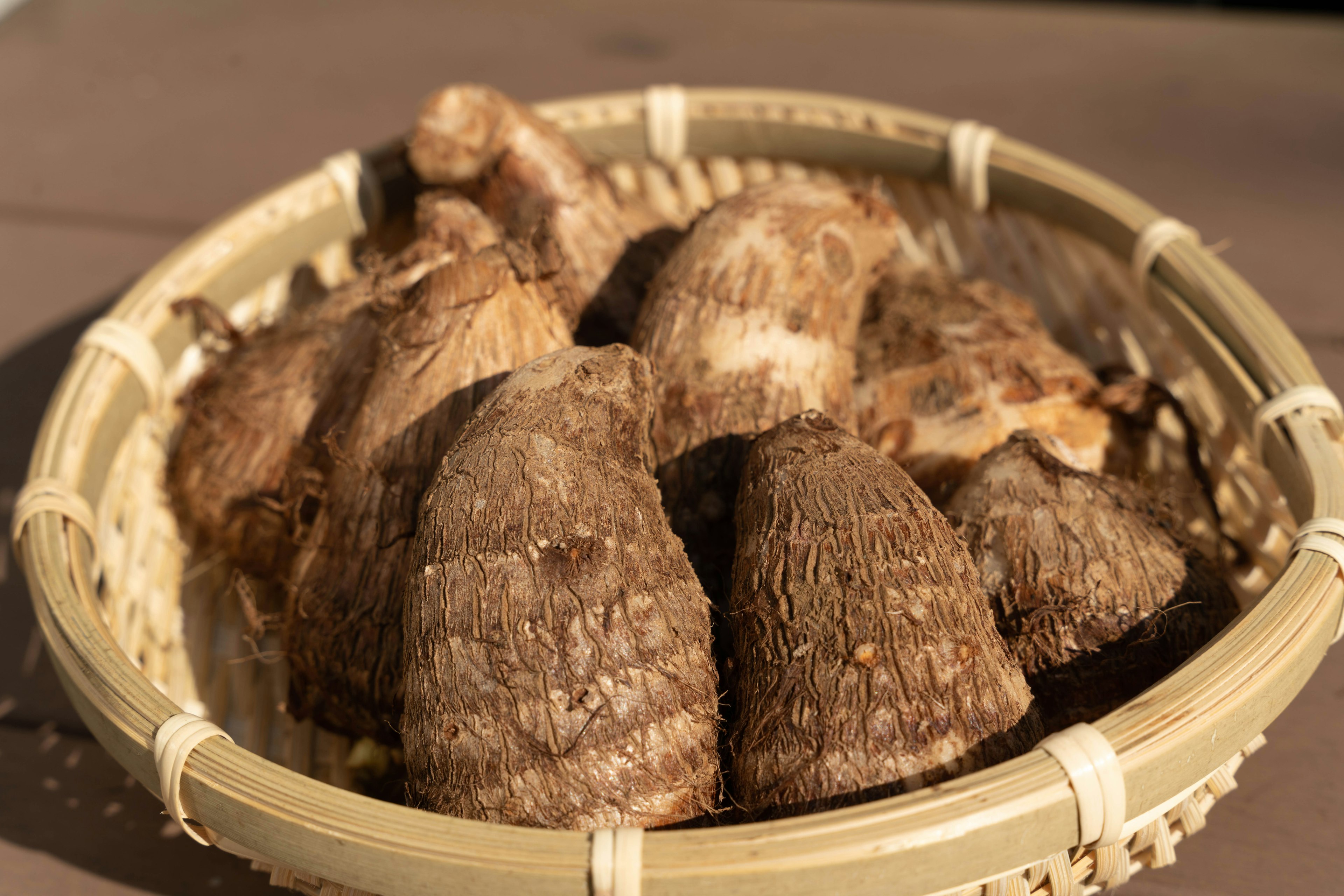 A bamboo basket filled with several dried root vegetables