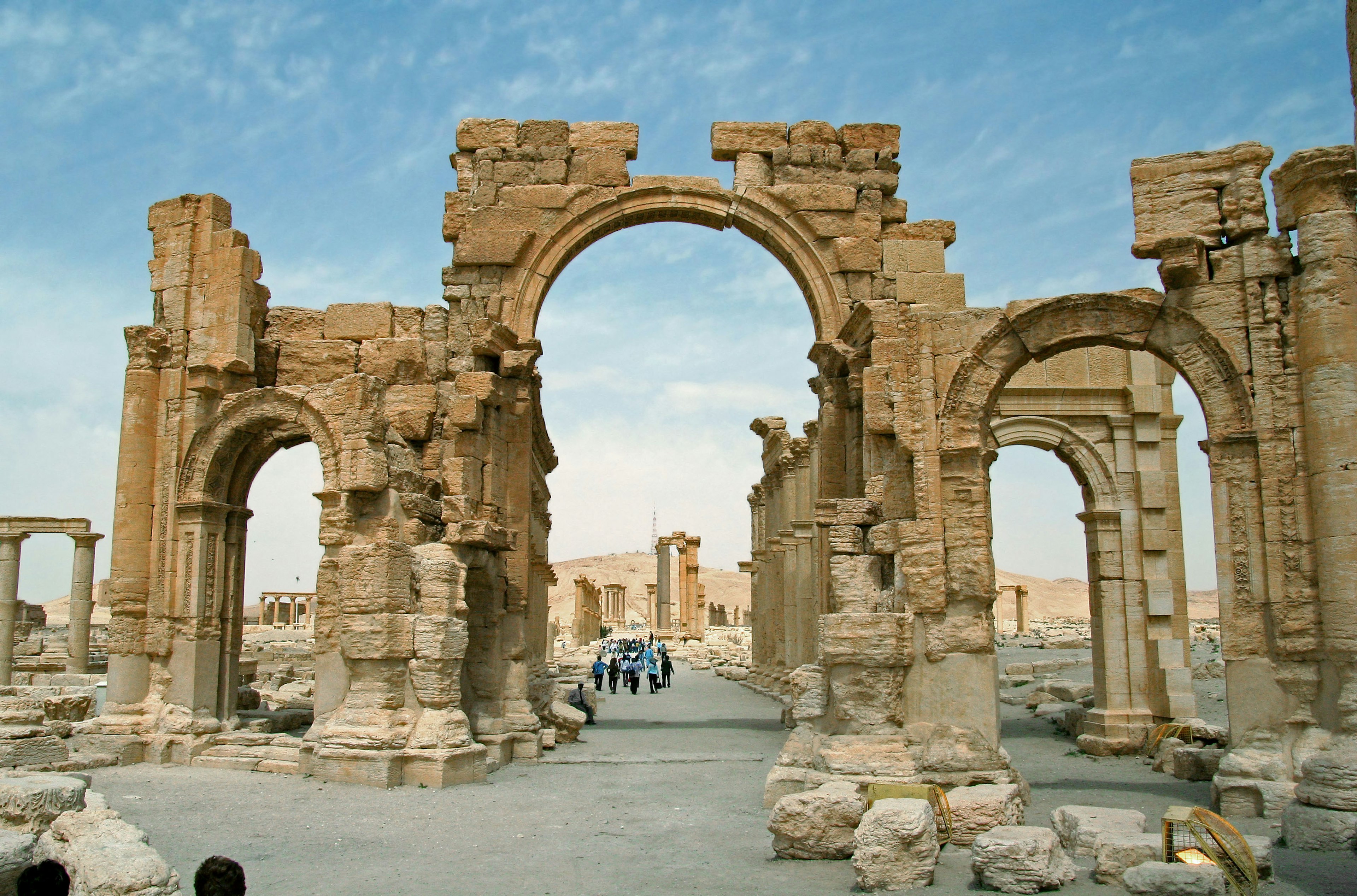 Ancient ruins featuring an arch and columns against a blue sky