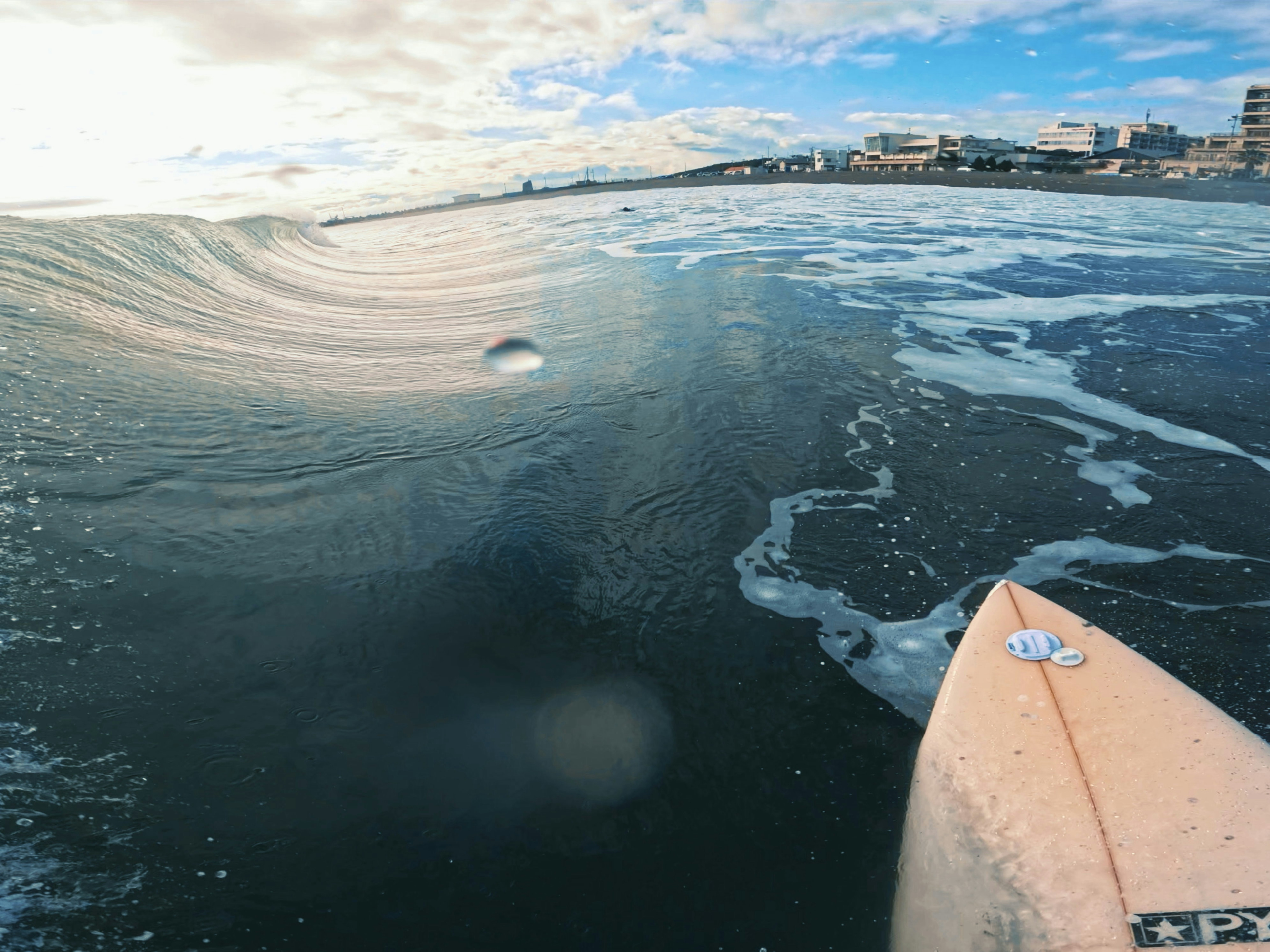 View of a surfboard tip and a wave in the ocean