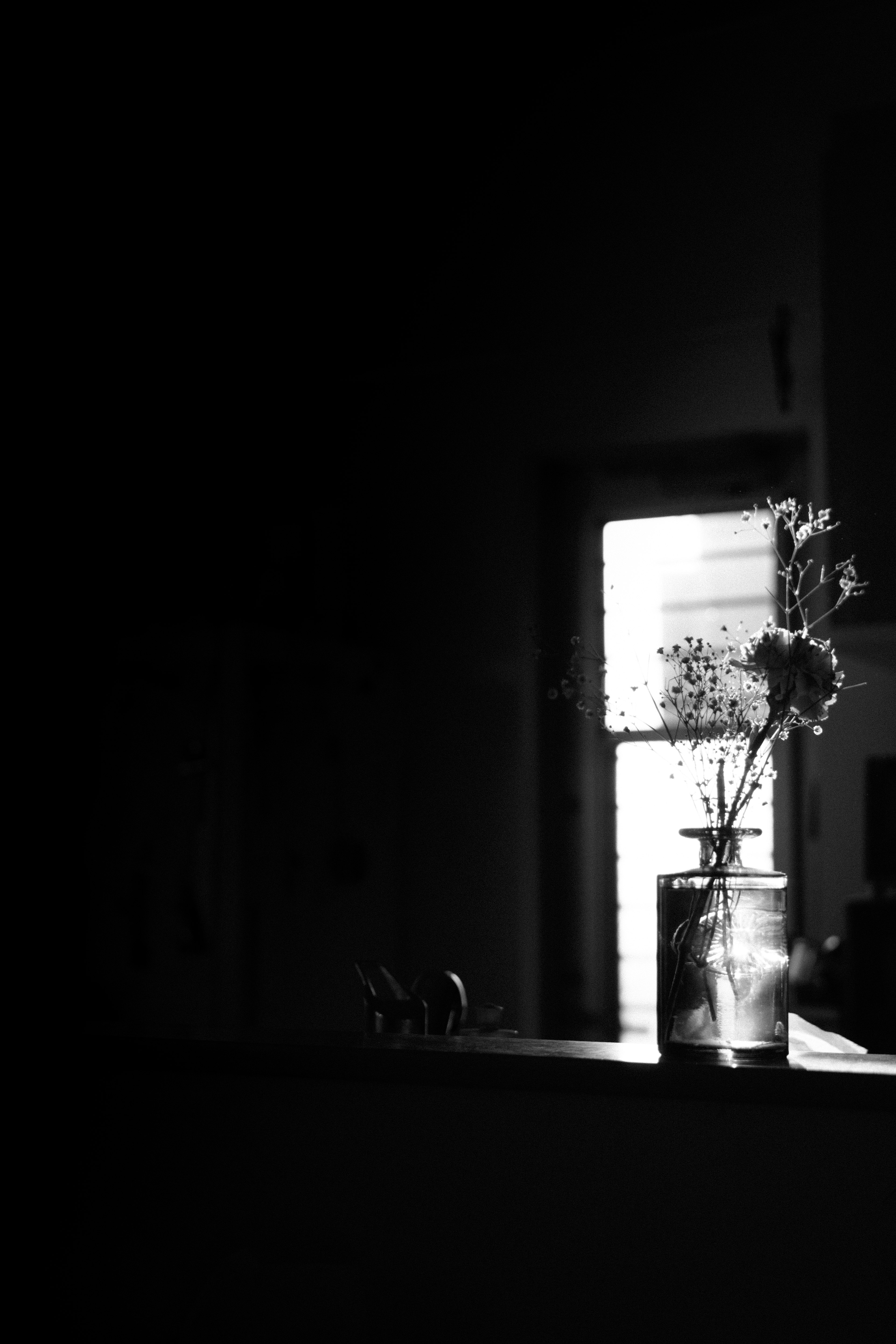 Ruhige Szene mit einer Vase voller Blumen auf einer Fensterbank in Schwarzweiß