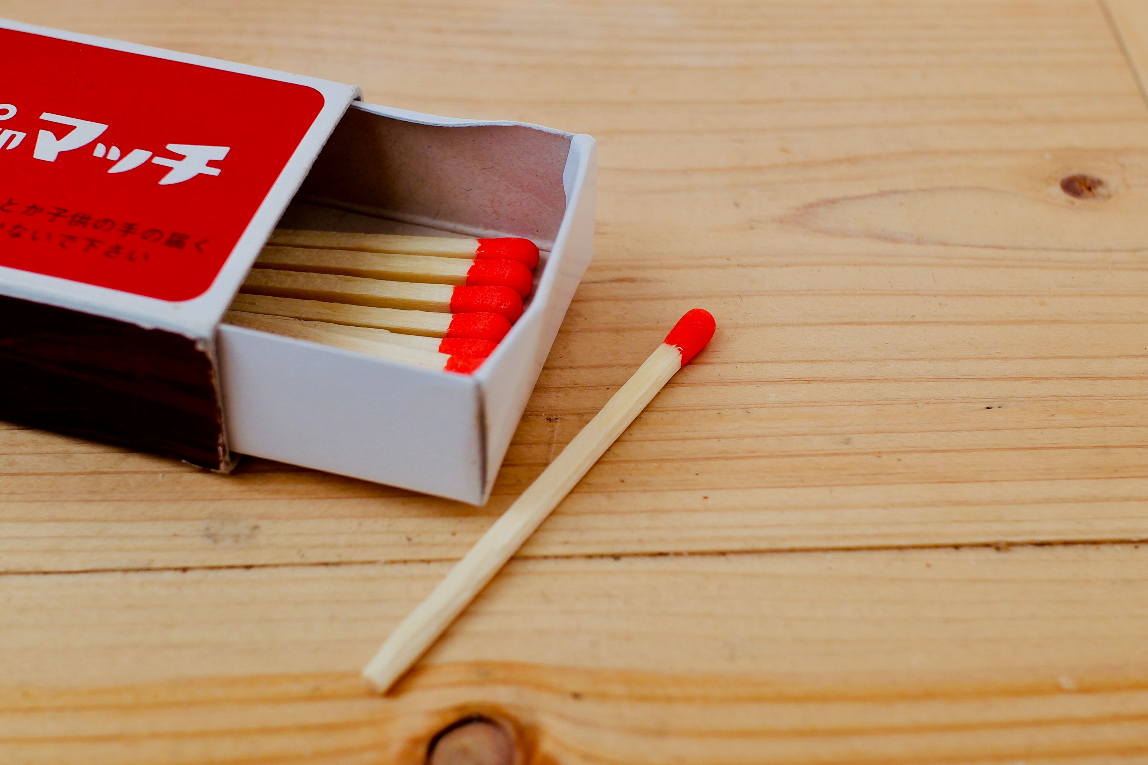 Matchbox with red matches and wooden table surface