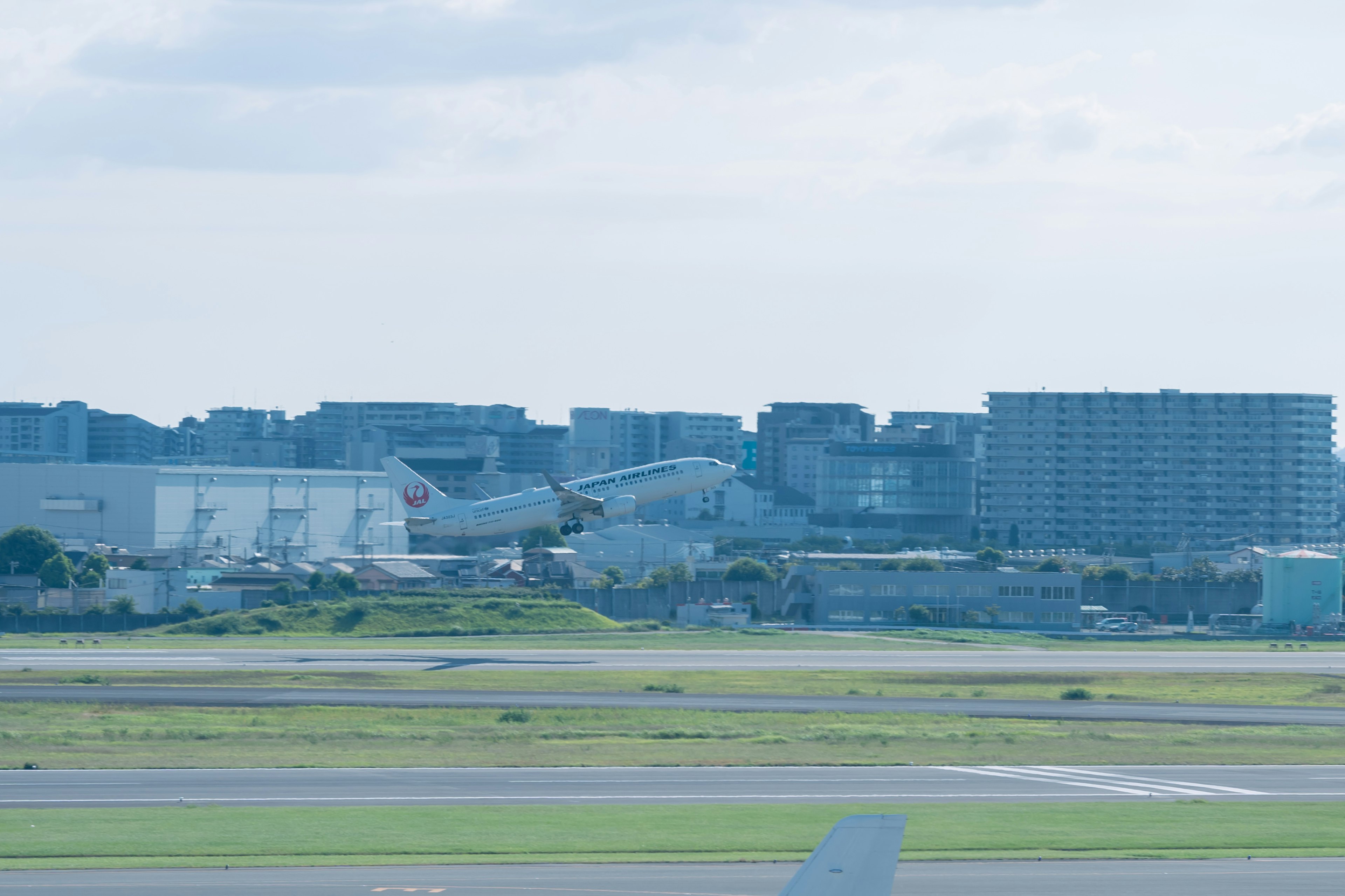 Aereo in decollo dalla pista con edifici sullo sfondo