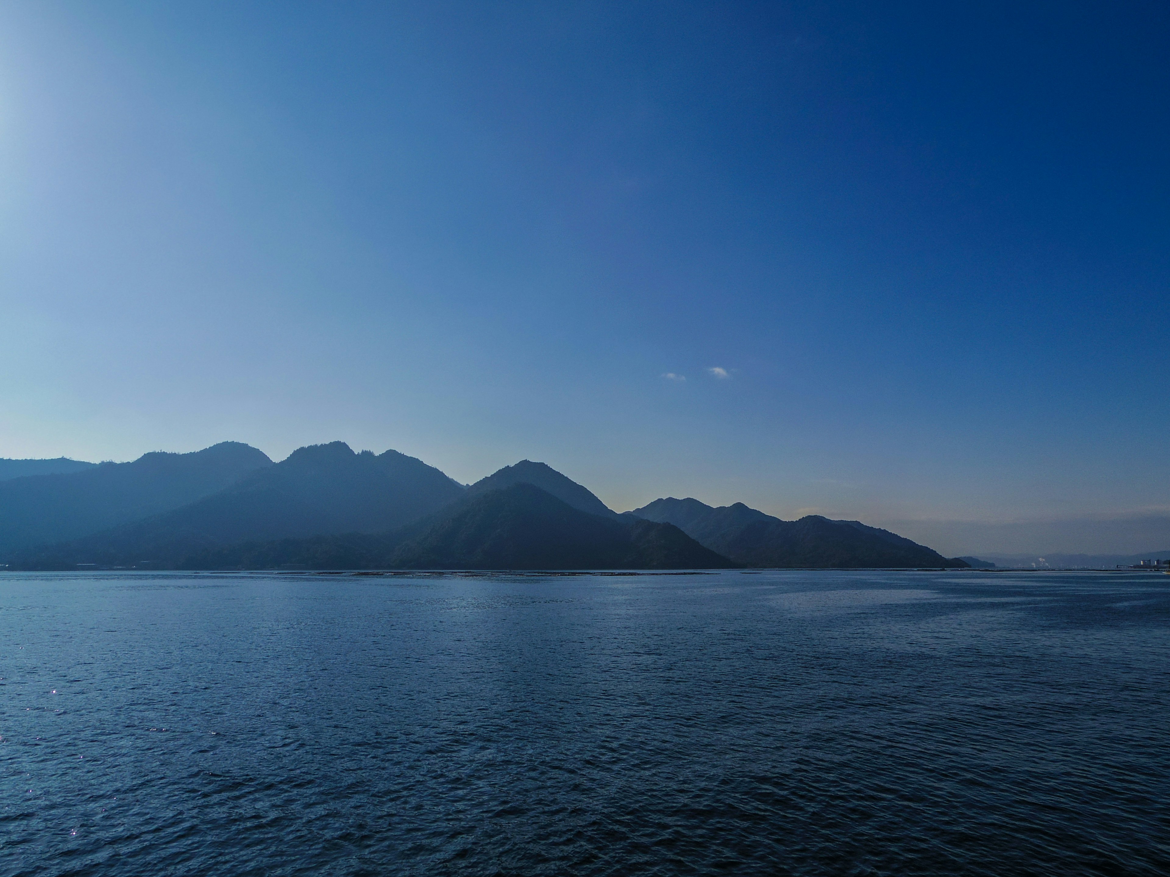 Vista panoramica di montagne riflesse in acqua blu calma sotto un cielo sereno