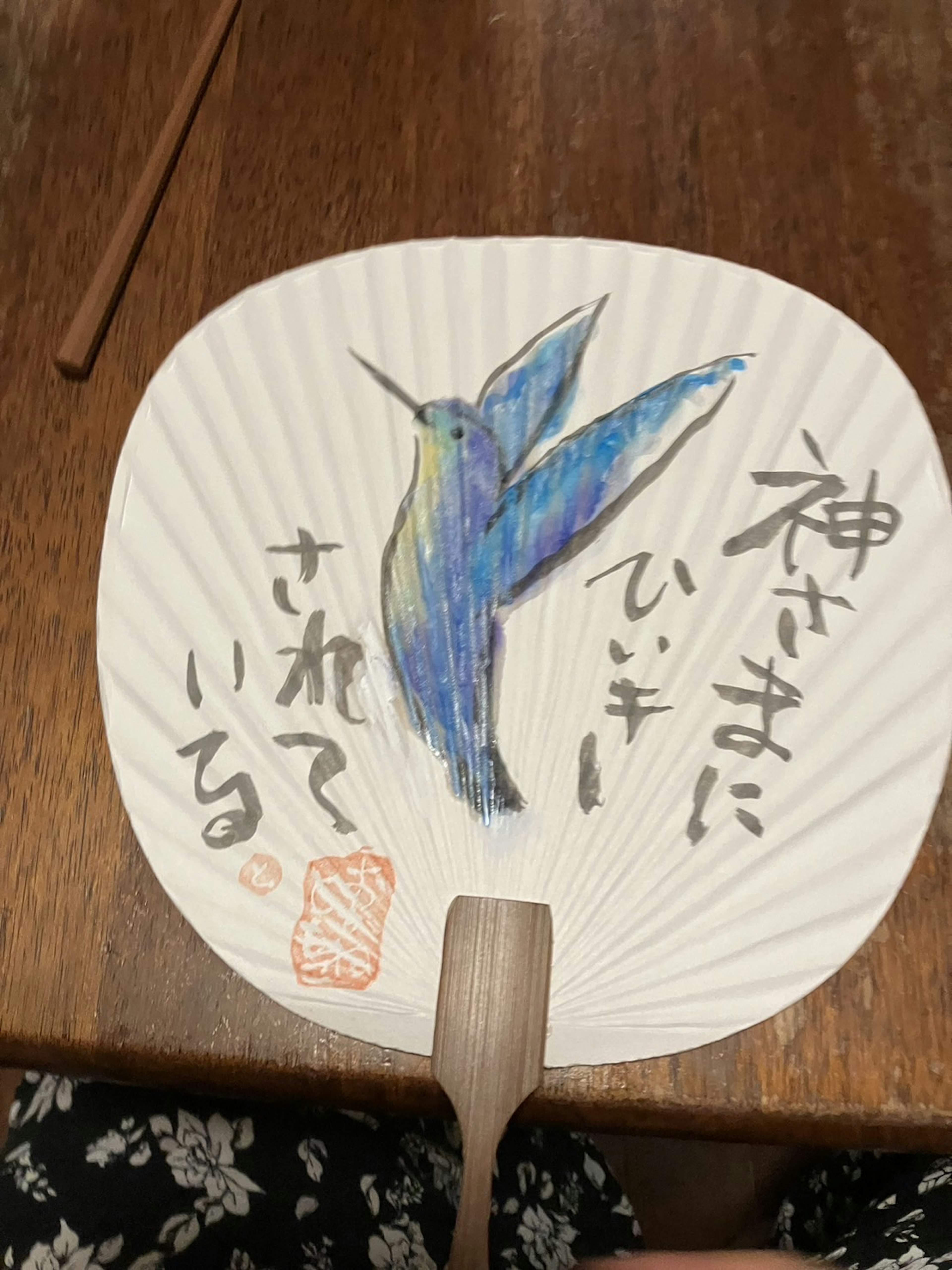 A traditional fan featuring a blue hummingbird illustration