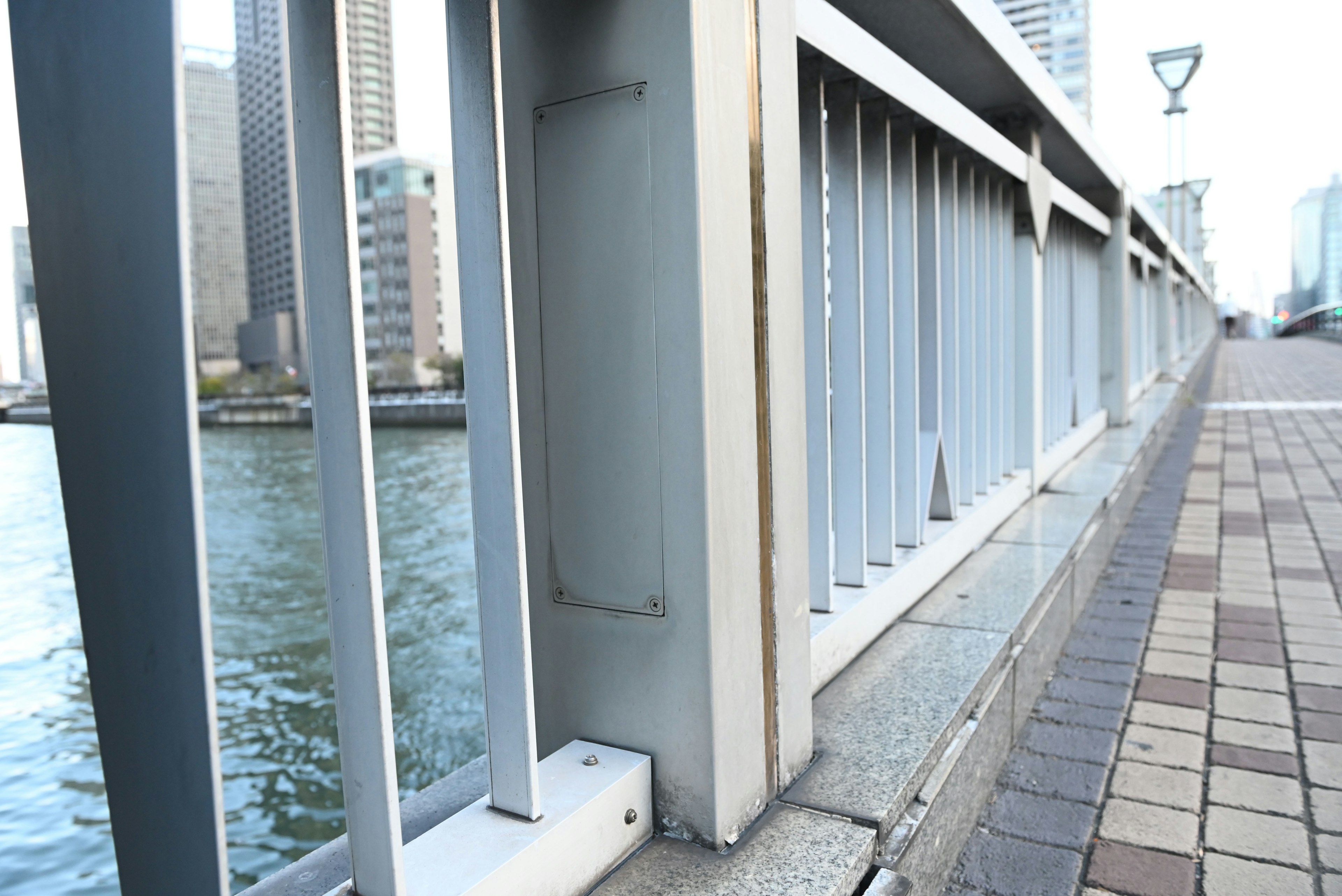 Close-up of a bridge railing and sidewalk near the river