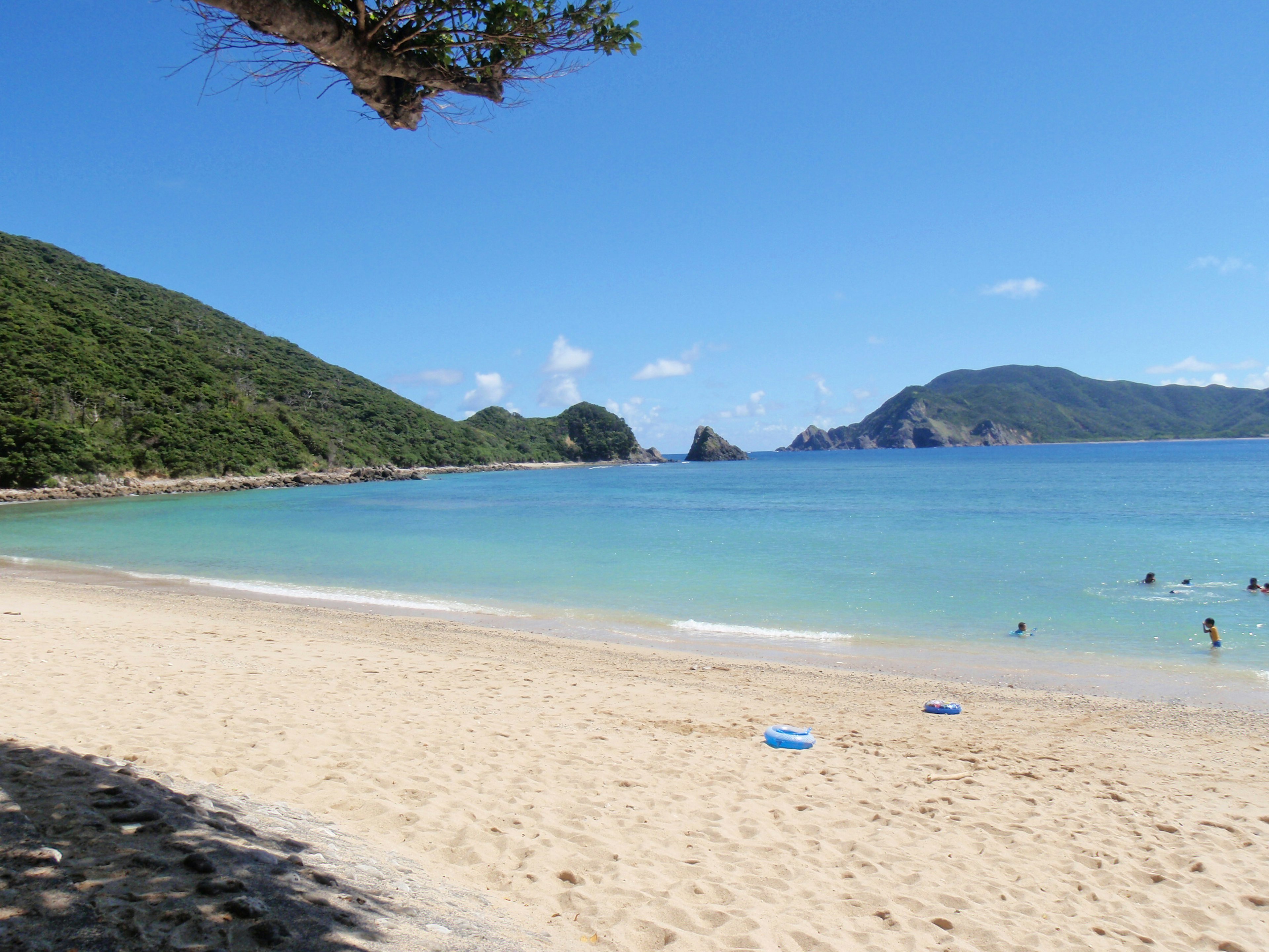 ทิวทัศน์ชายหาดที่สวยงามมีทะเลสีน้ำเงินและชายหาดทรายภูเขาสีเขียวและเกาะห่างไกล