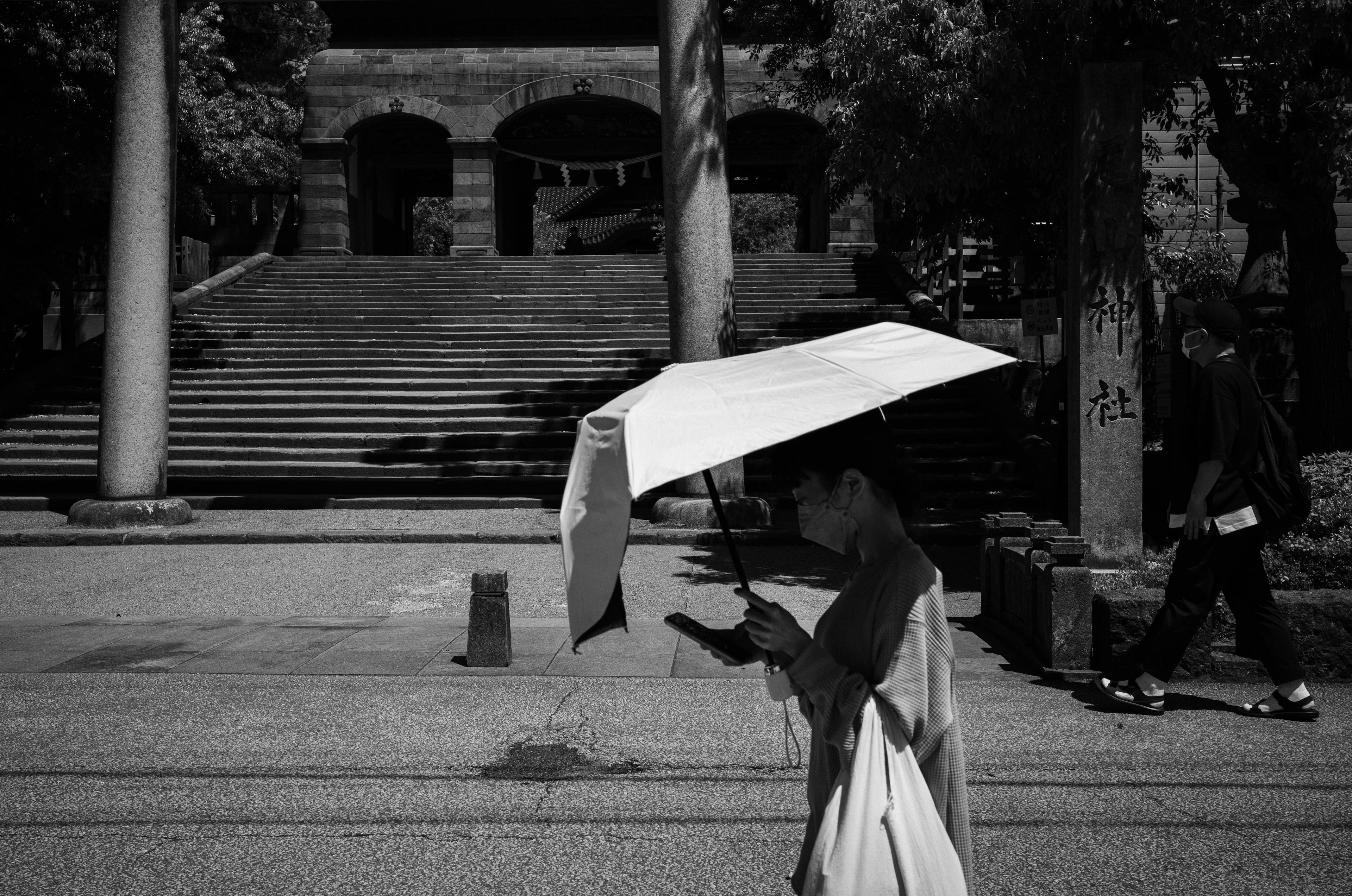 Persona caminando con un paraguas blanco en un entorno en blanco y negro con escaleras