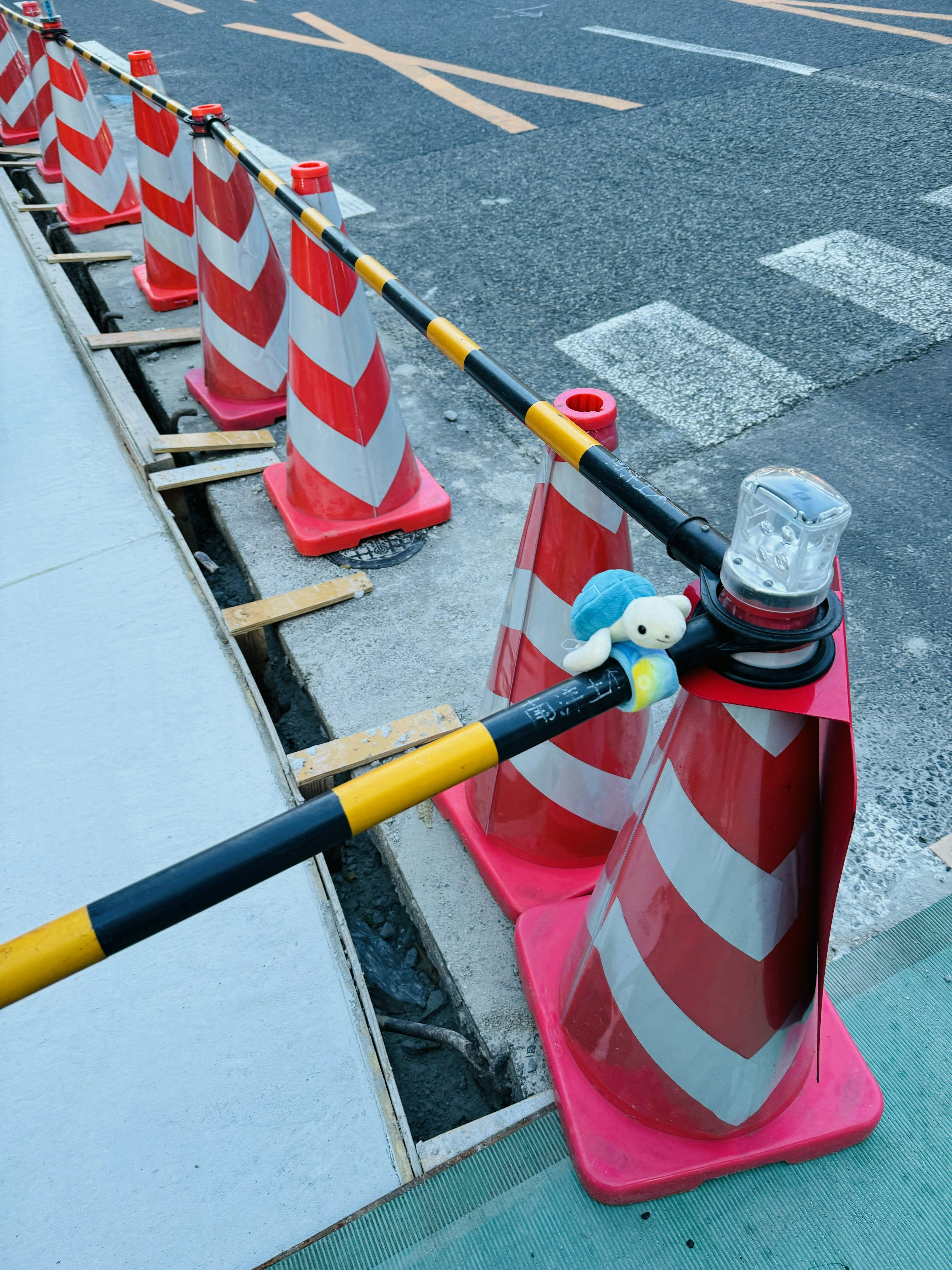 Reihe von roten und weißen Baustellenmarkierungen mit einem blauen Plüschcharakter und einem klaren Licht auf einem Kegel