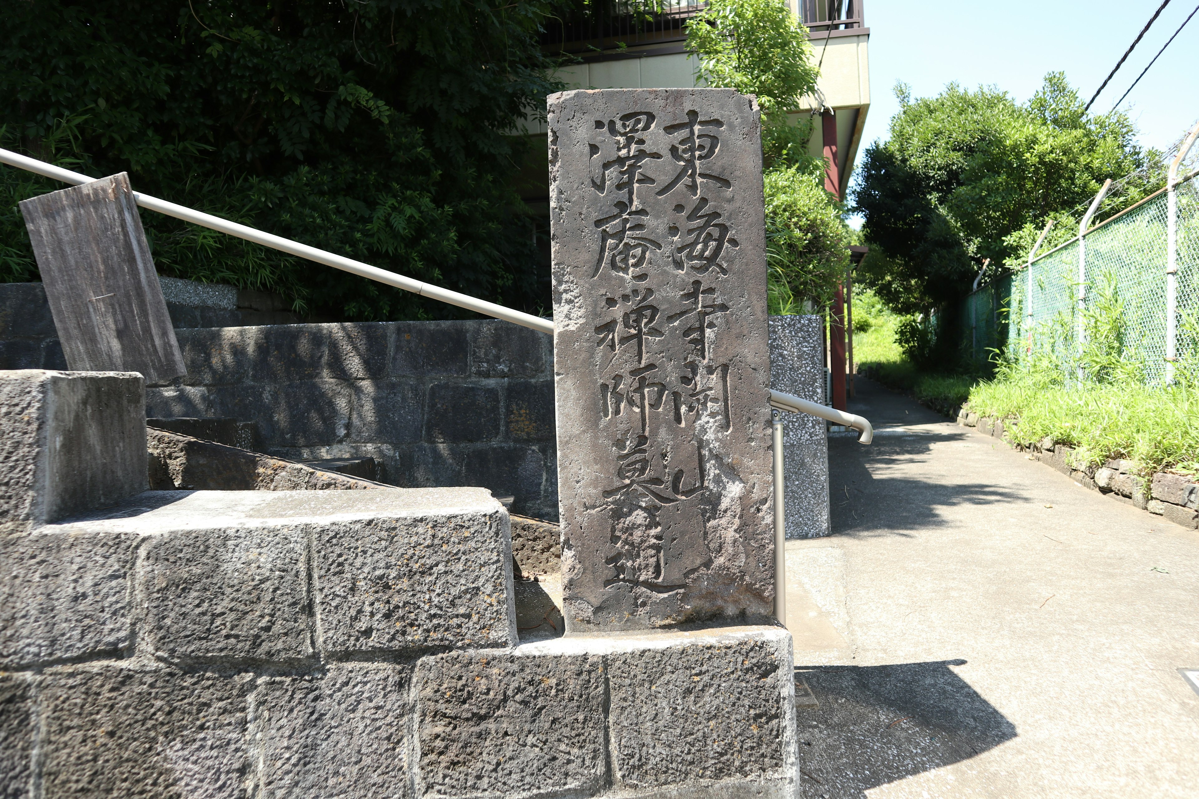 Ein Steinmonument mit Inschriften neben einem schmalen Weg