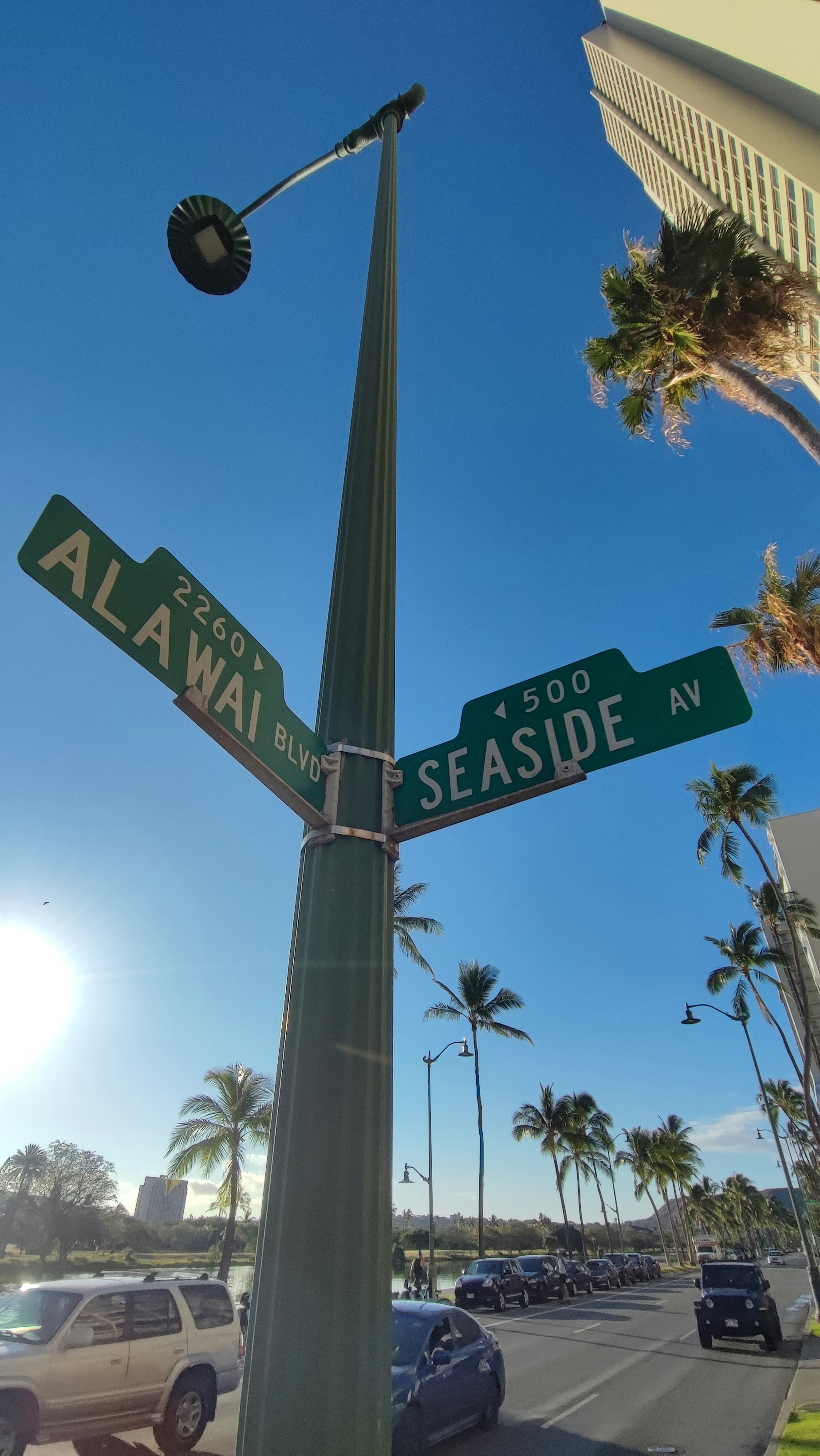 Señal de intersección de Alawai y Seaside con palmeras al fondo