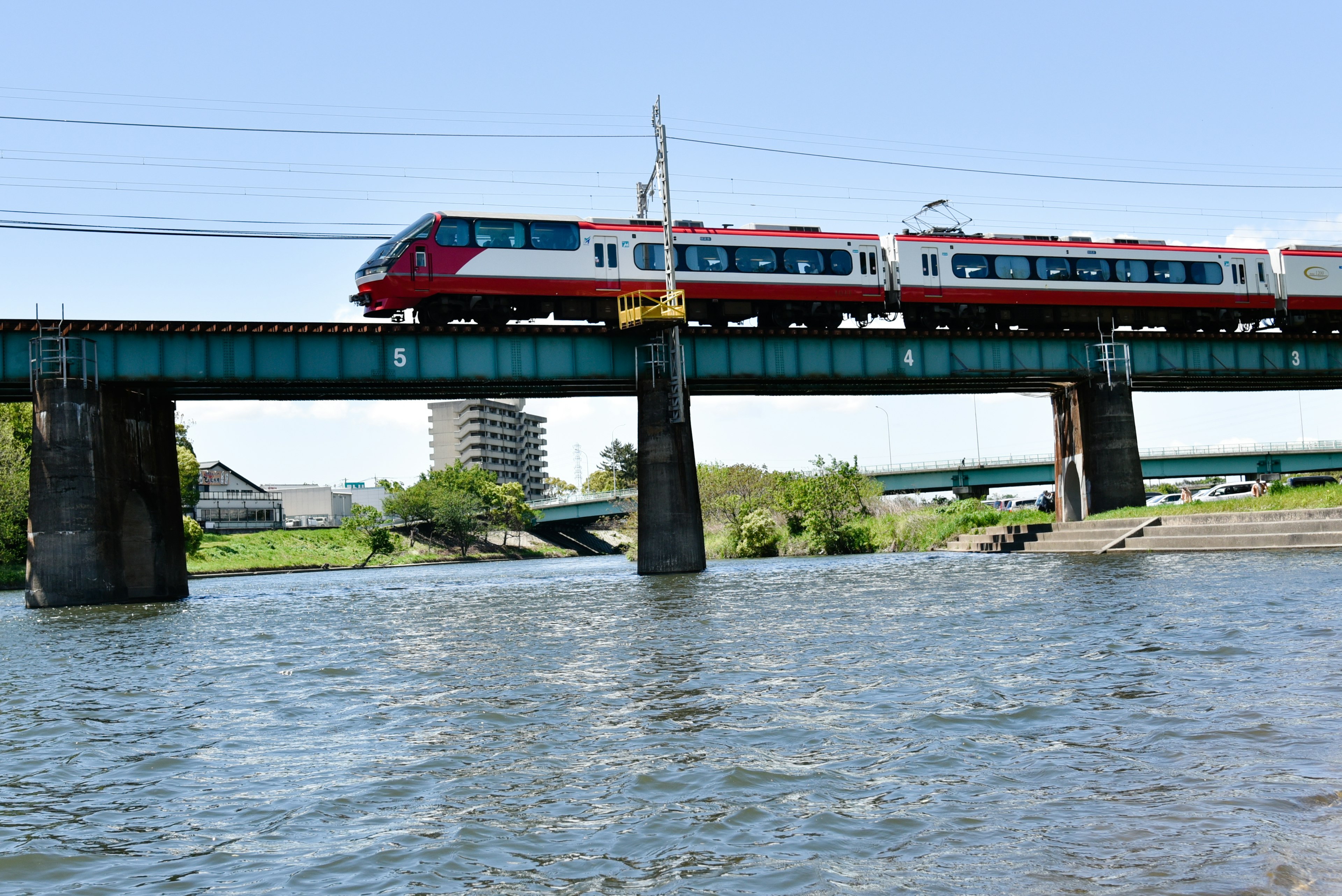 赤い電車が川の上の橋を渡っている風景