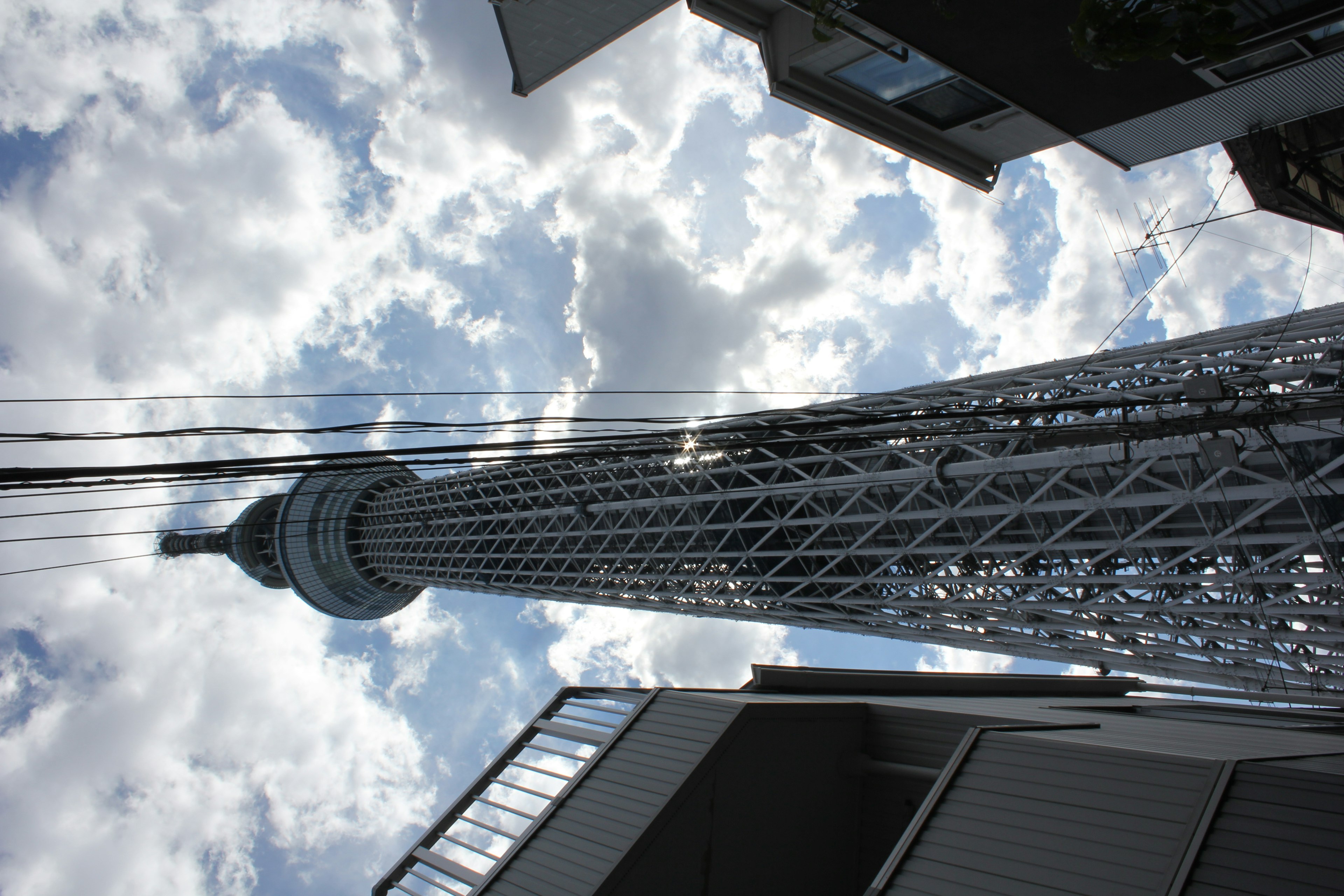 Blick von unten auf den Tokyo Skytree umgeben von blauem Himmel und Wolken