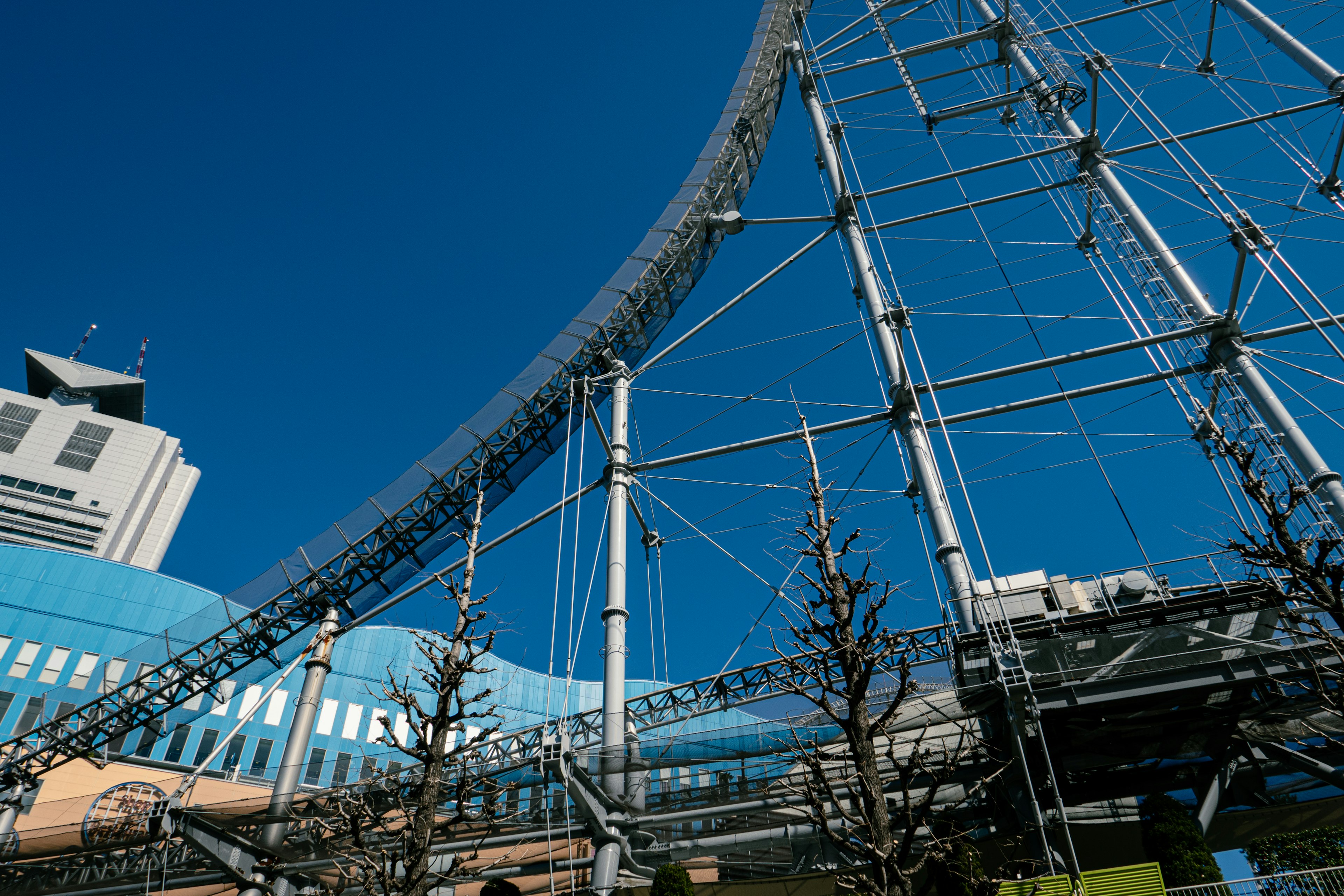 Bangunan modern dan struktur roller coaster melengkung di bawah langit biru