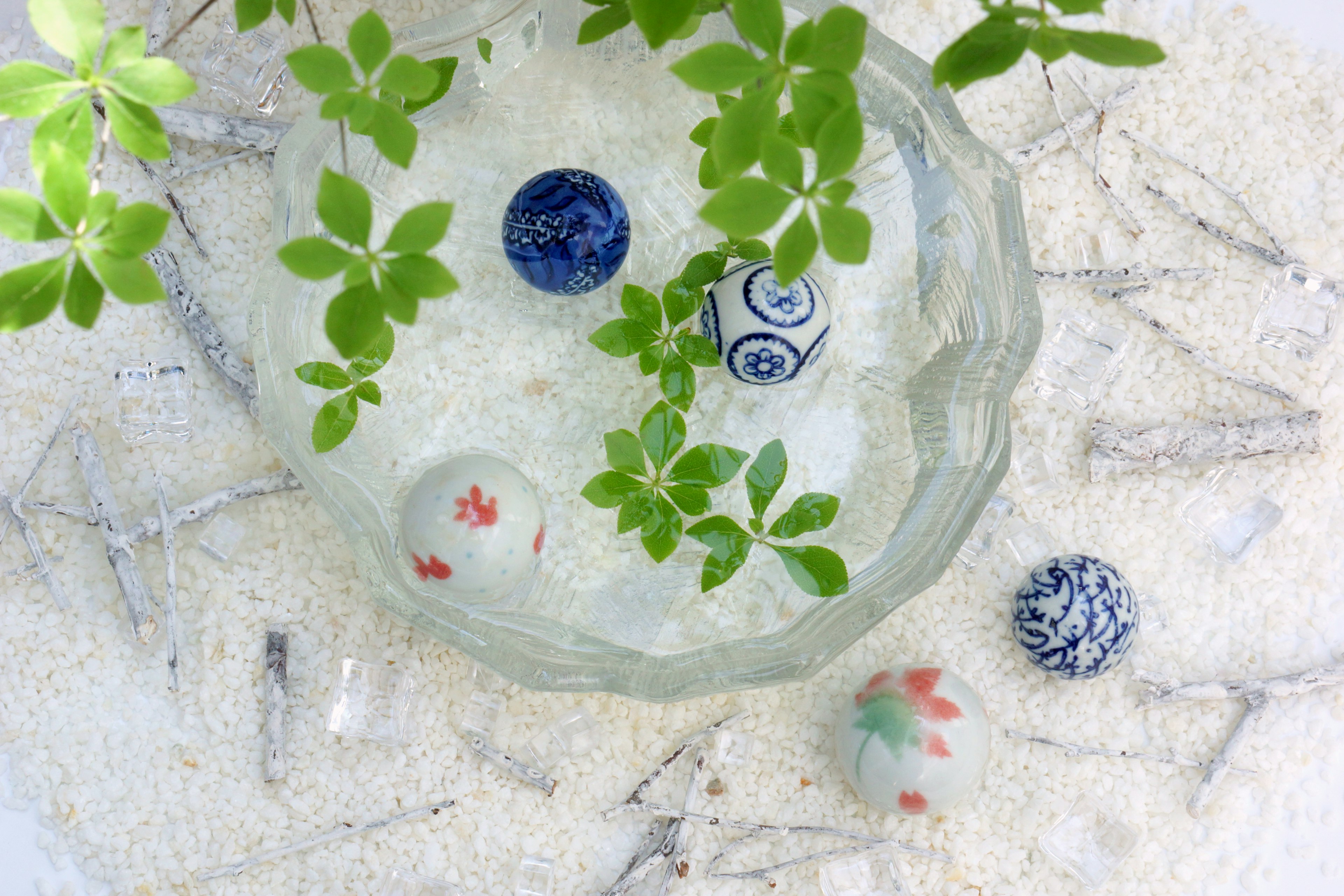 Colorful marbles floating in a clear dish with green leaves