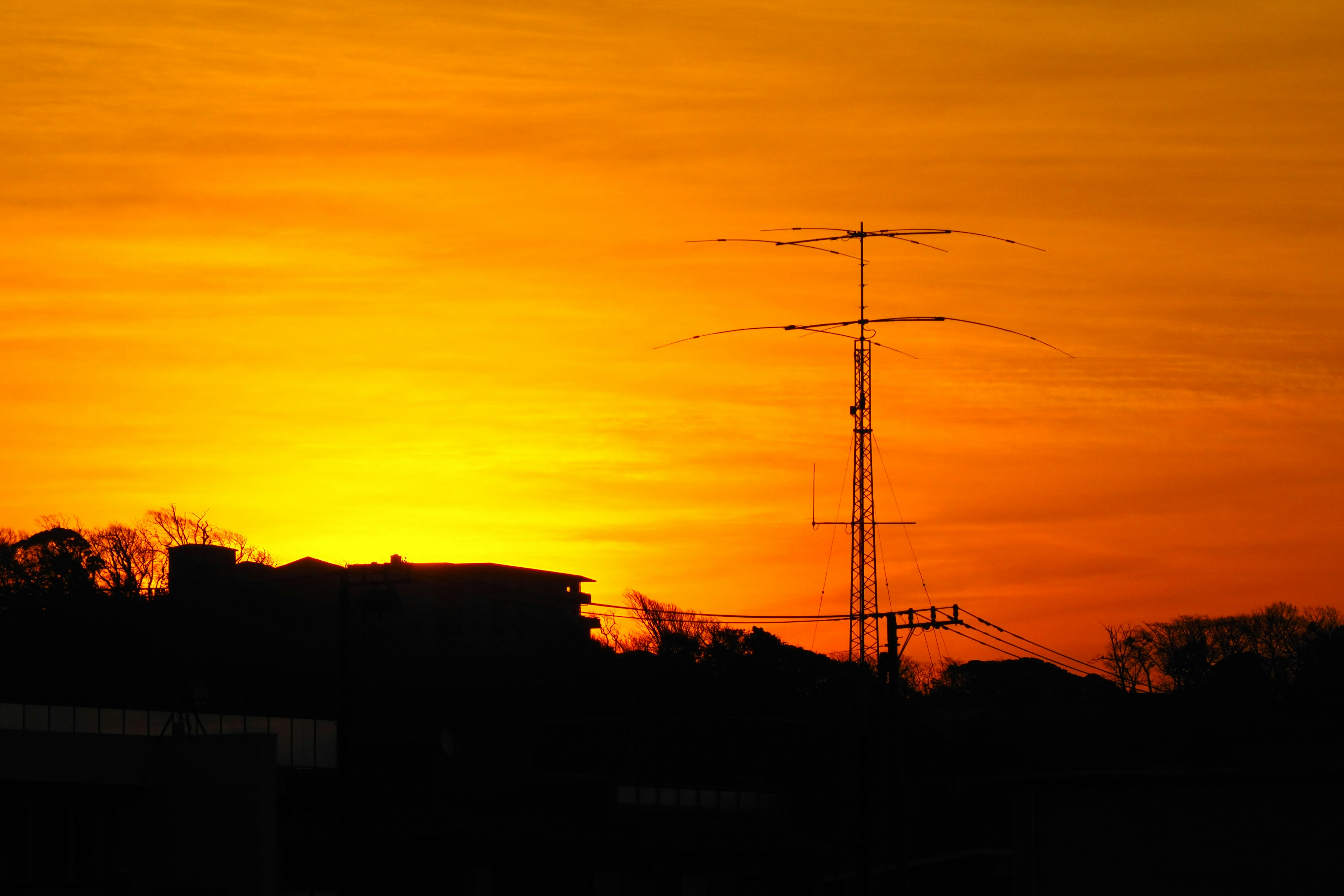 Sonnenuntergangshimmel mit Silhouette von Gebäuden und Kommunikationsmast