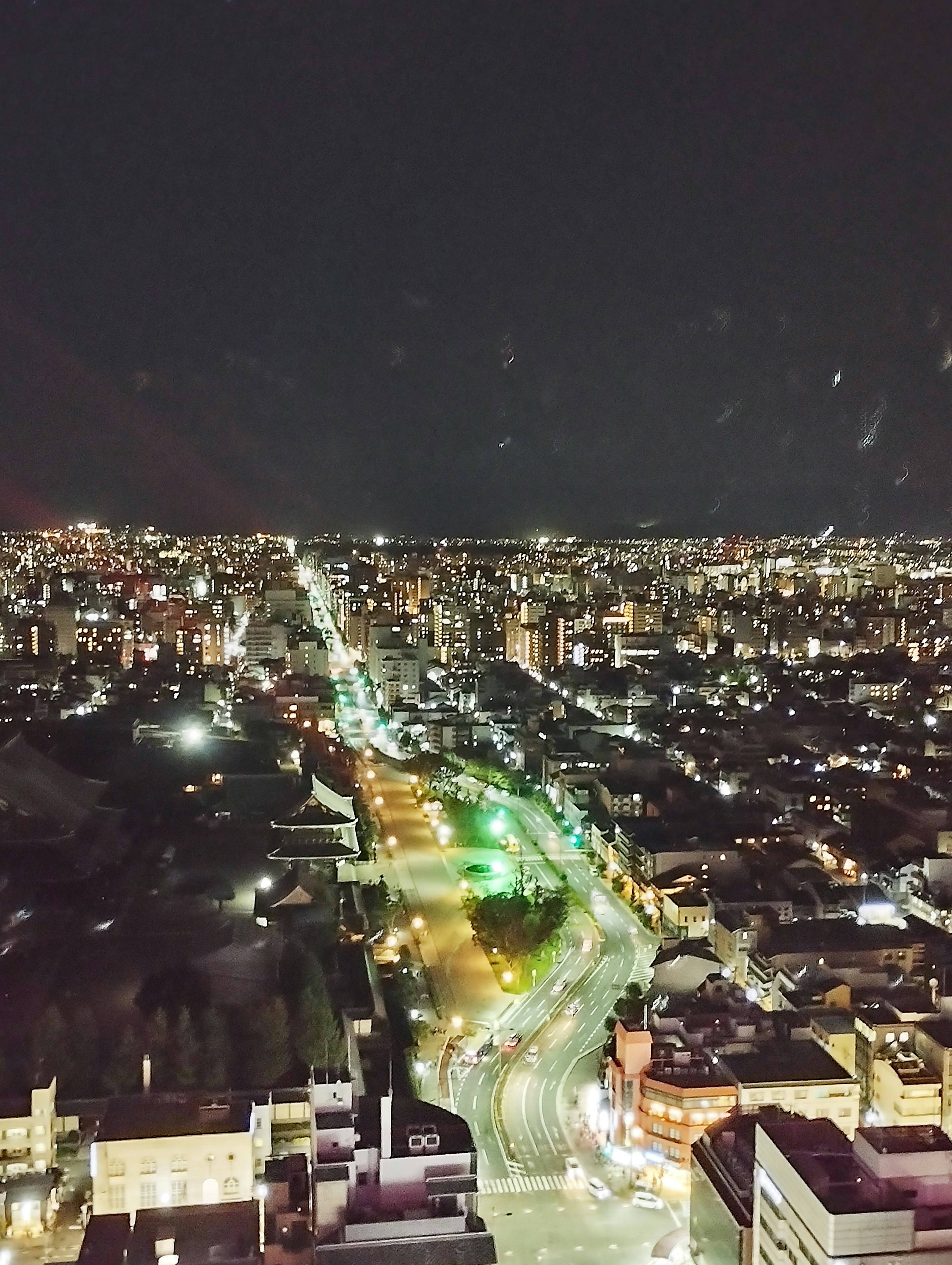 Nighttime cityscape with bright streetlights and green traffic signals