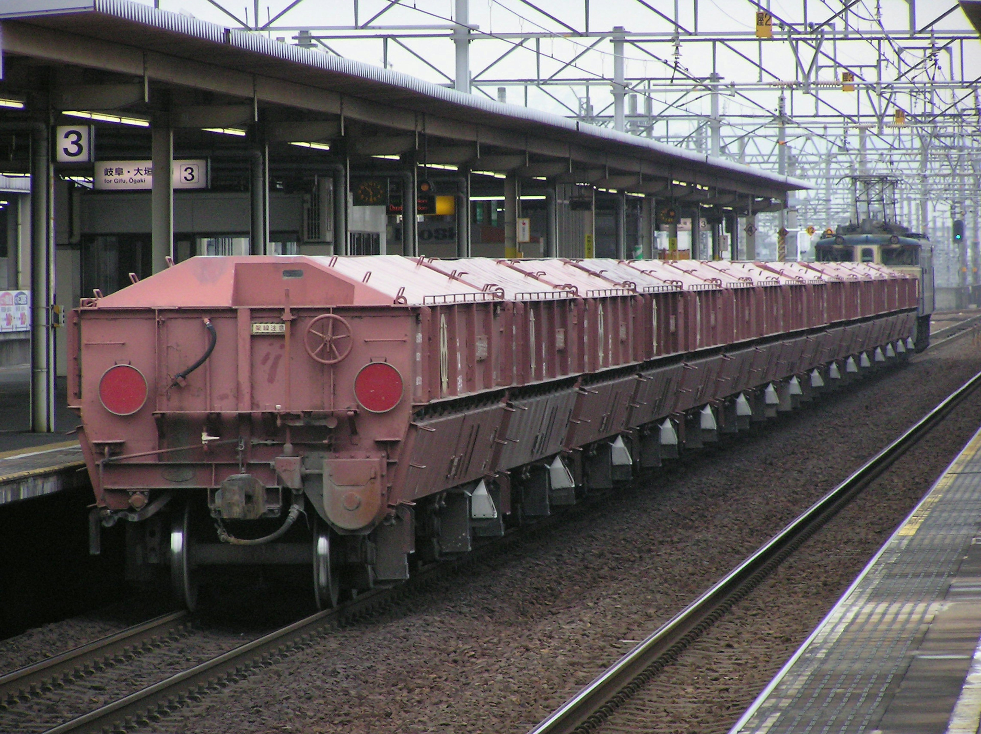 Roter Güterzug, der am Bahnsteig hält