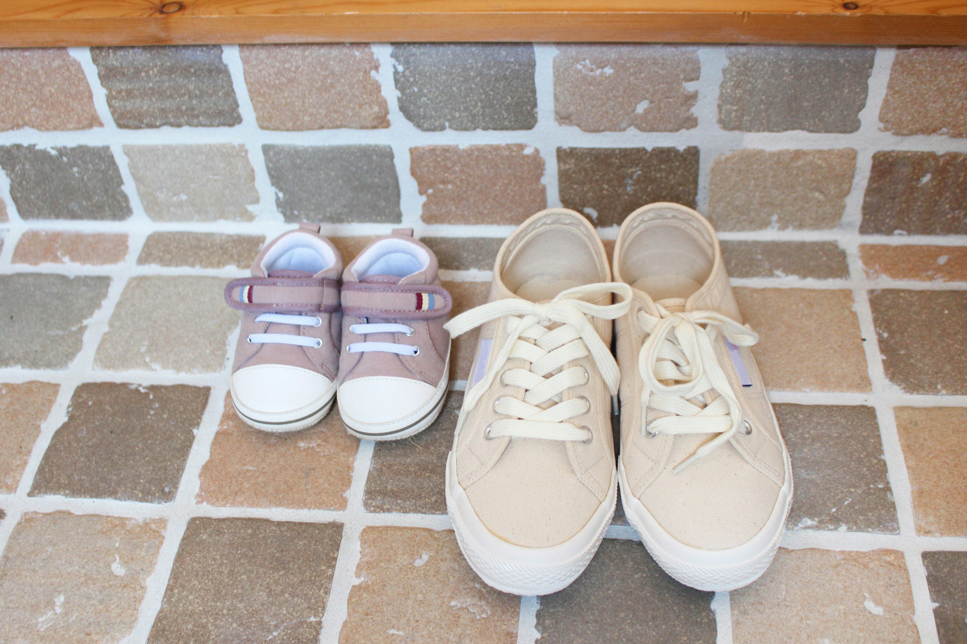 A pair of beige sneakers and a small pair of children's sneakers side by side