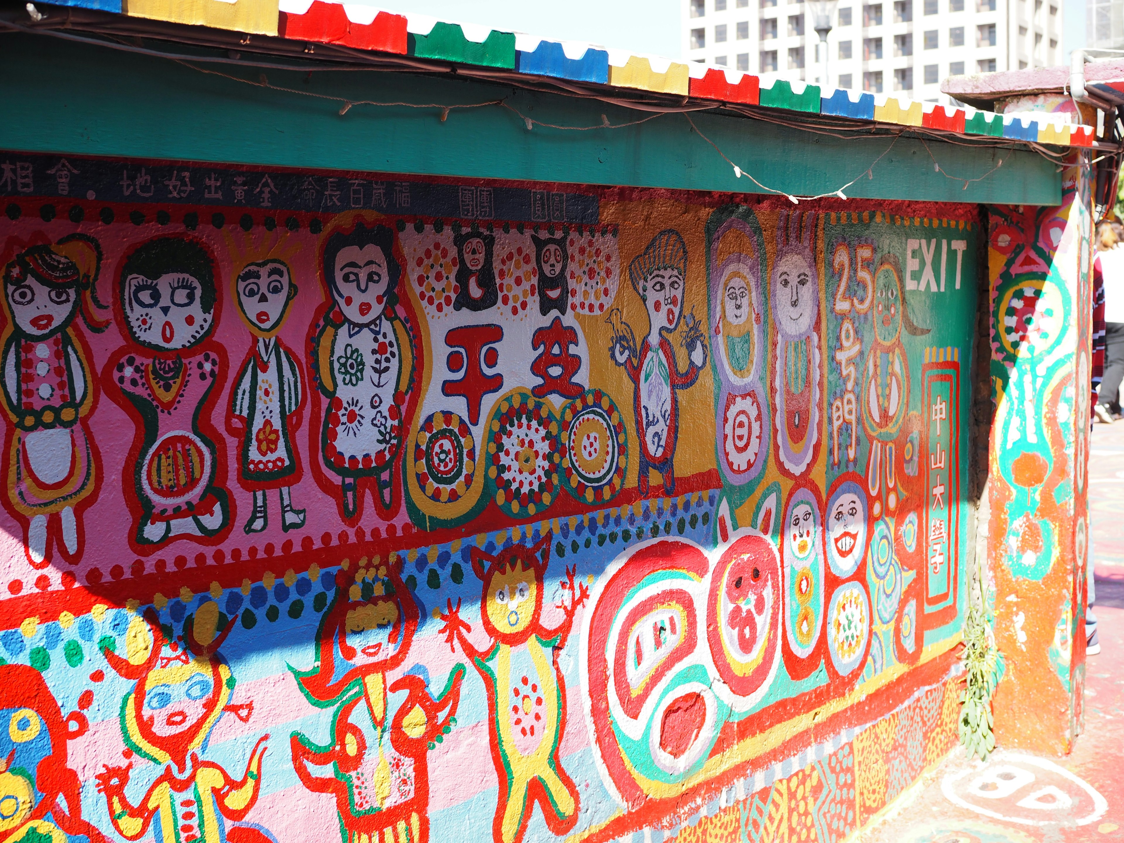 Colorful wall mural depicting various figures and patterns on a building