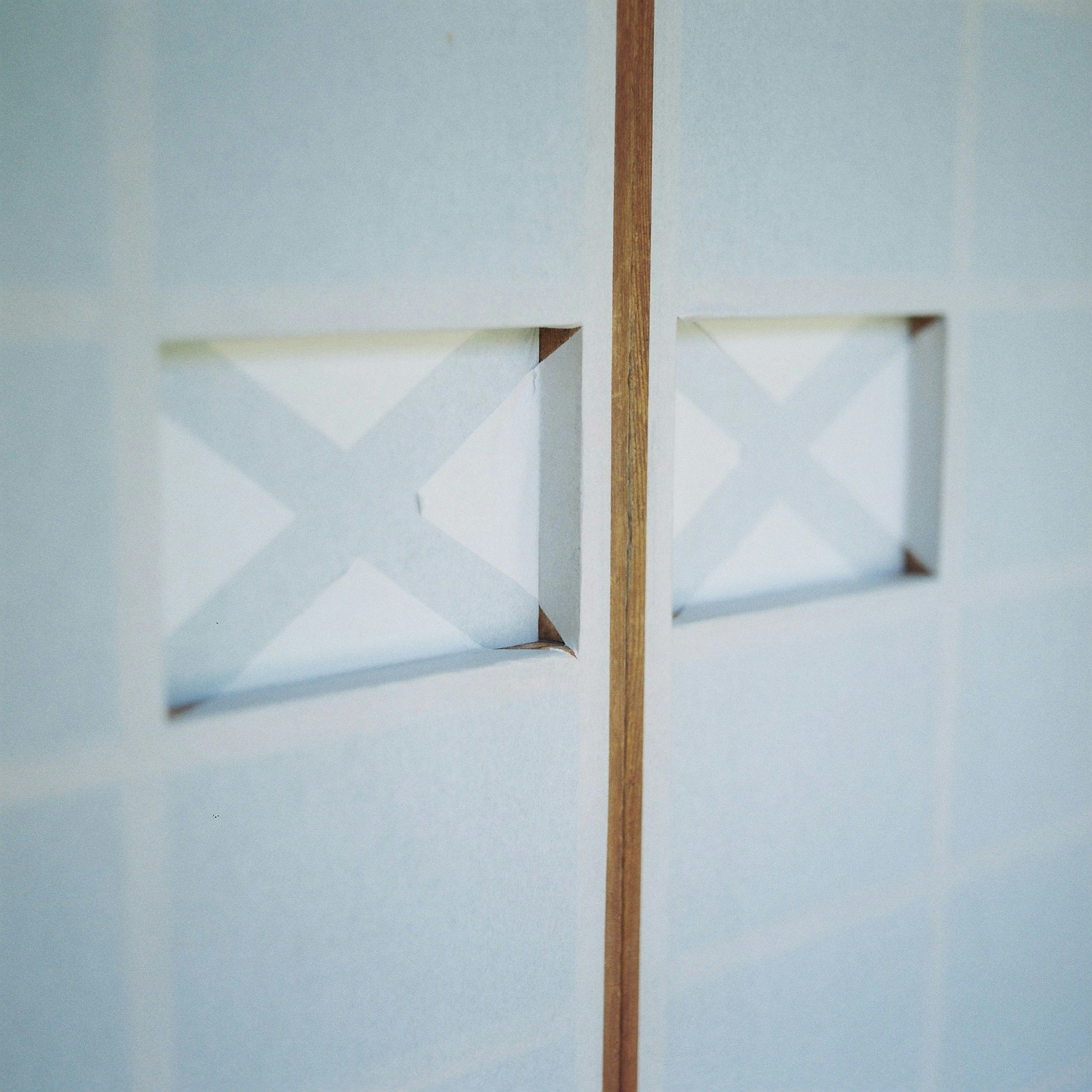 Two square openings in a white wall with wooden divider