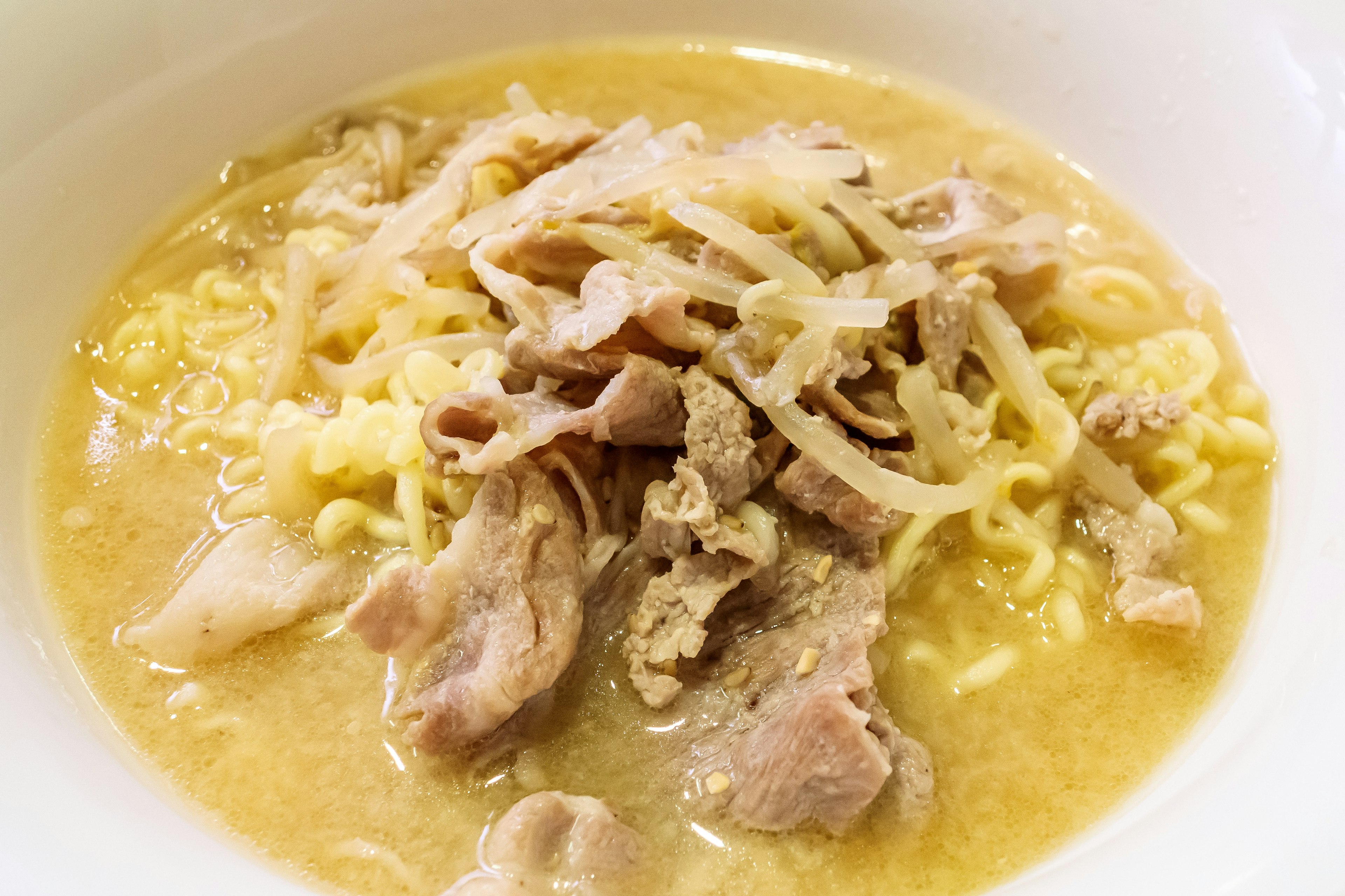 Bowl of ramen with pork slices and shredded vegetables in broth