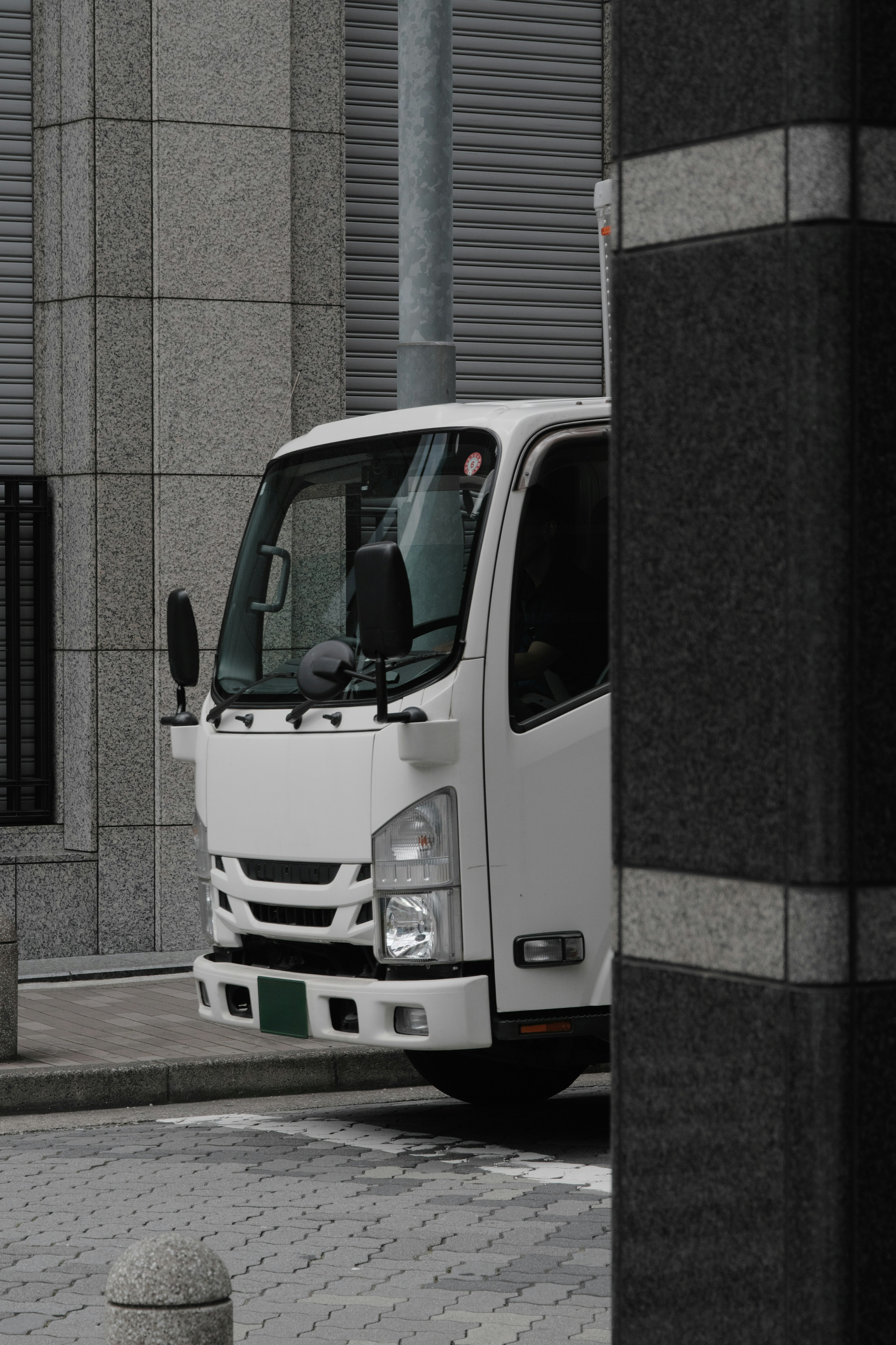 White truck emerging from the corner of a building