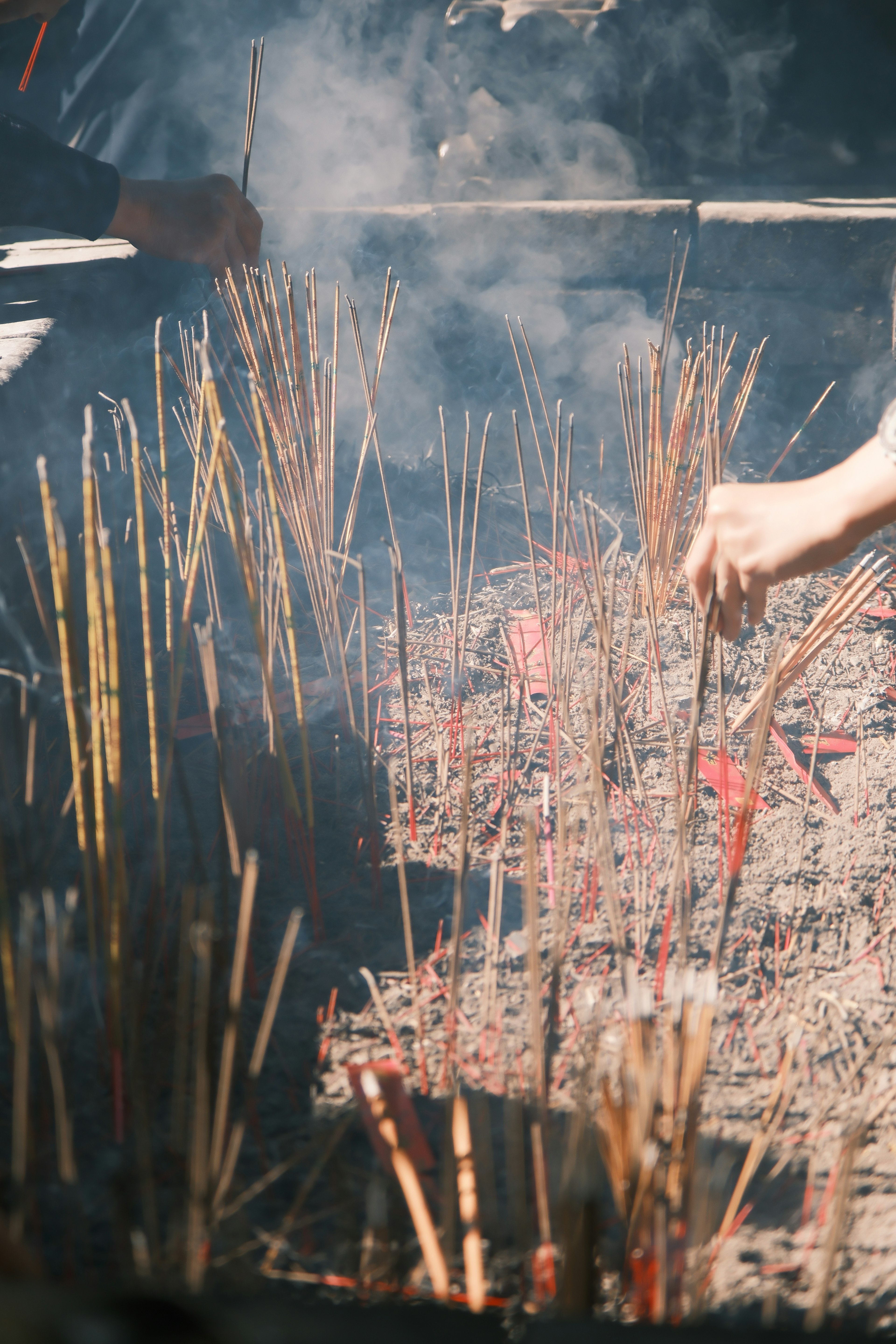 Hands placing incense sticks in a smoky setting