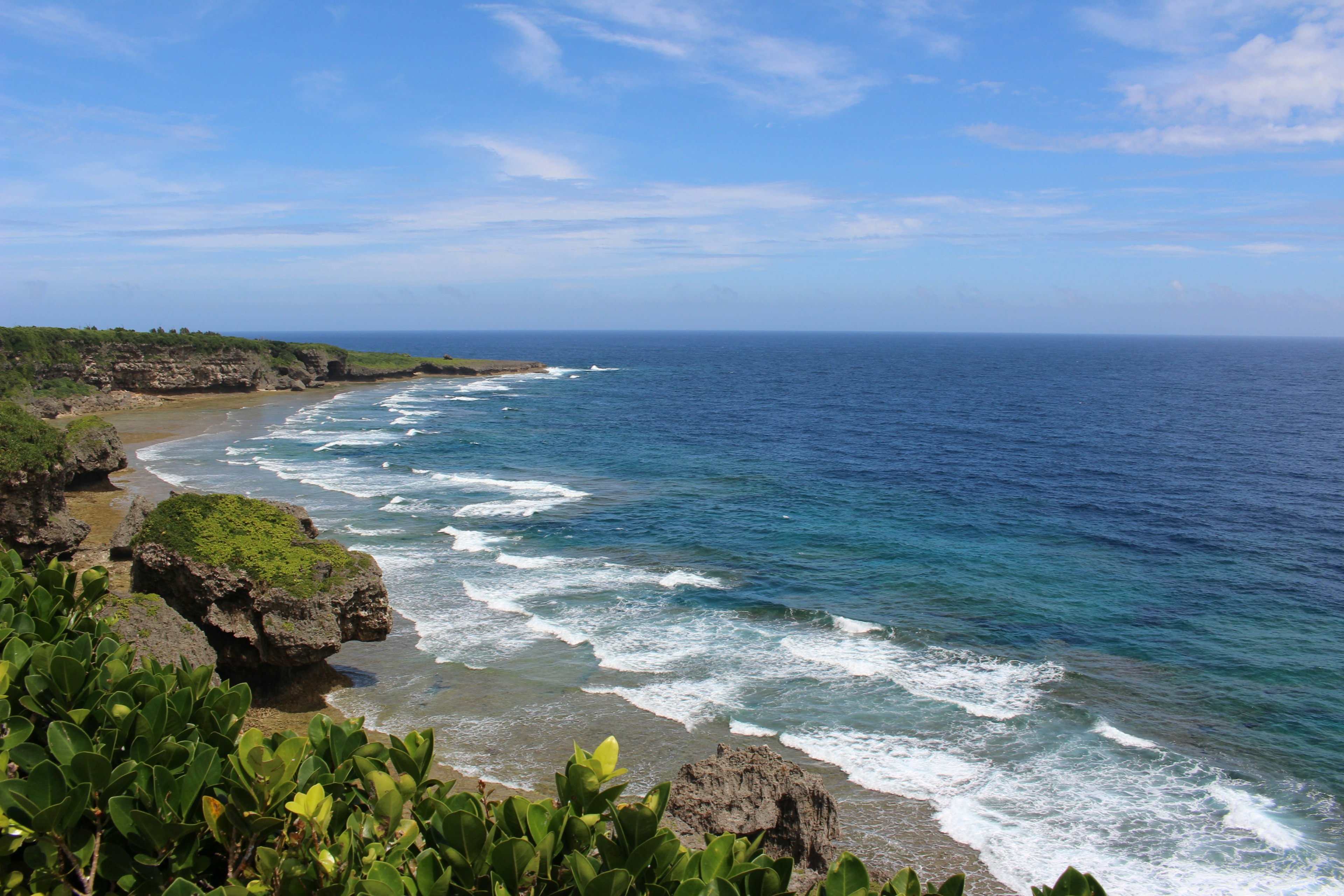 Pemandangan pantai dengan lautan biru dan ombak menghantam tebing