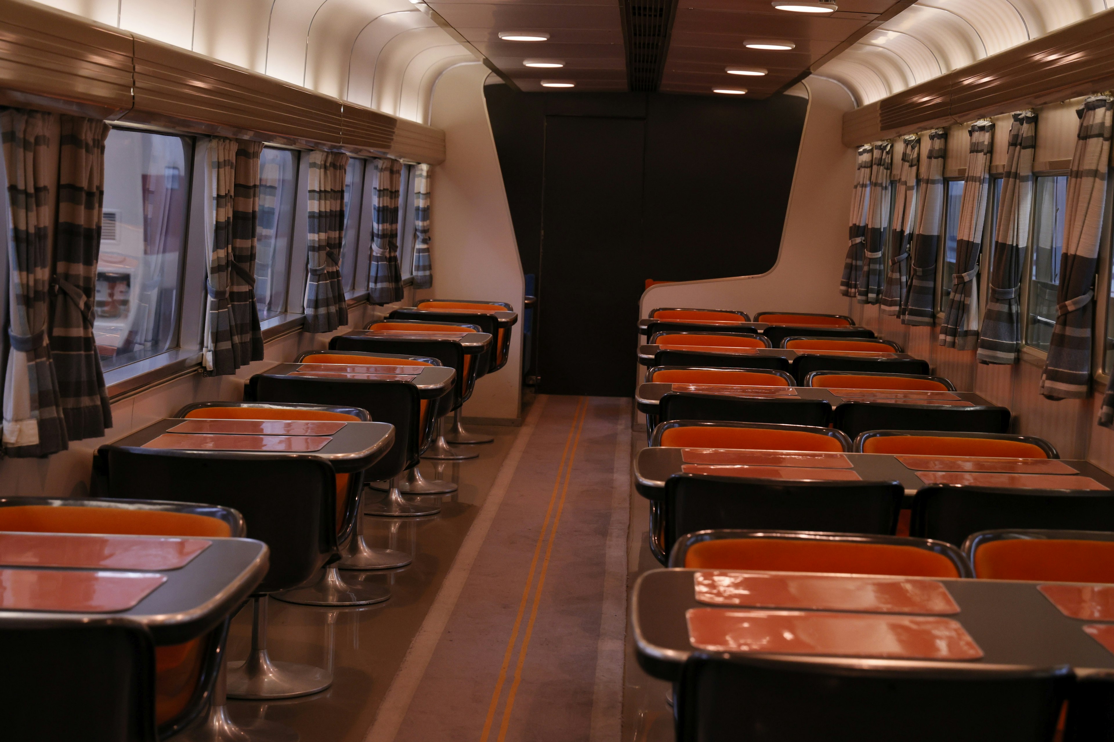 Interior of a train dining car with bright tables and chairs