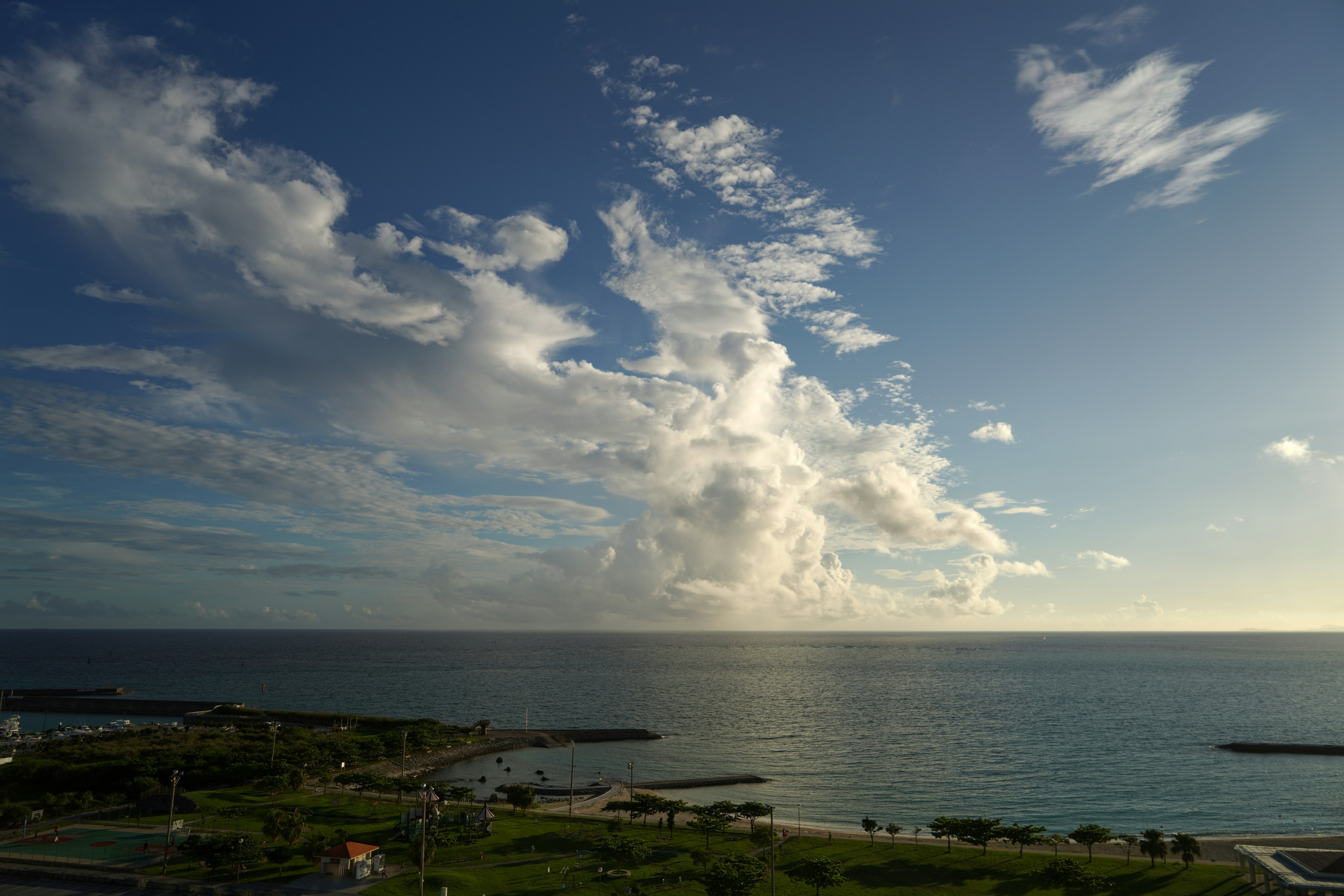 青い海と広がる雲の風景 緑の草地と遠くの岸が見える