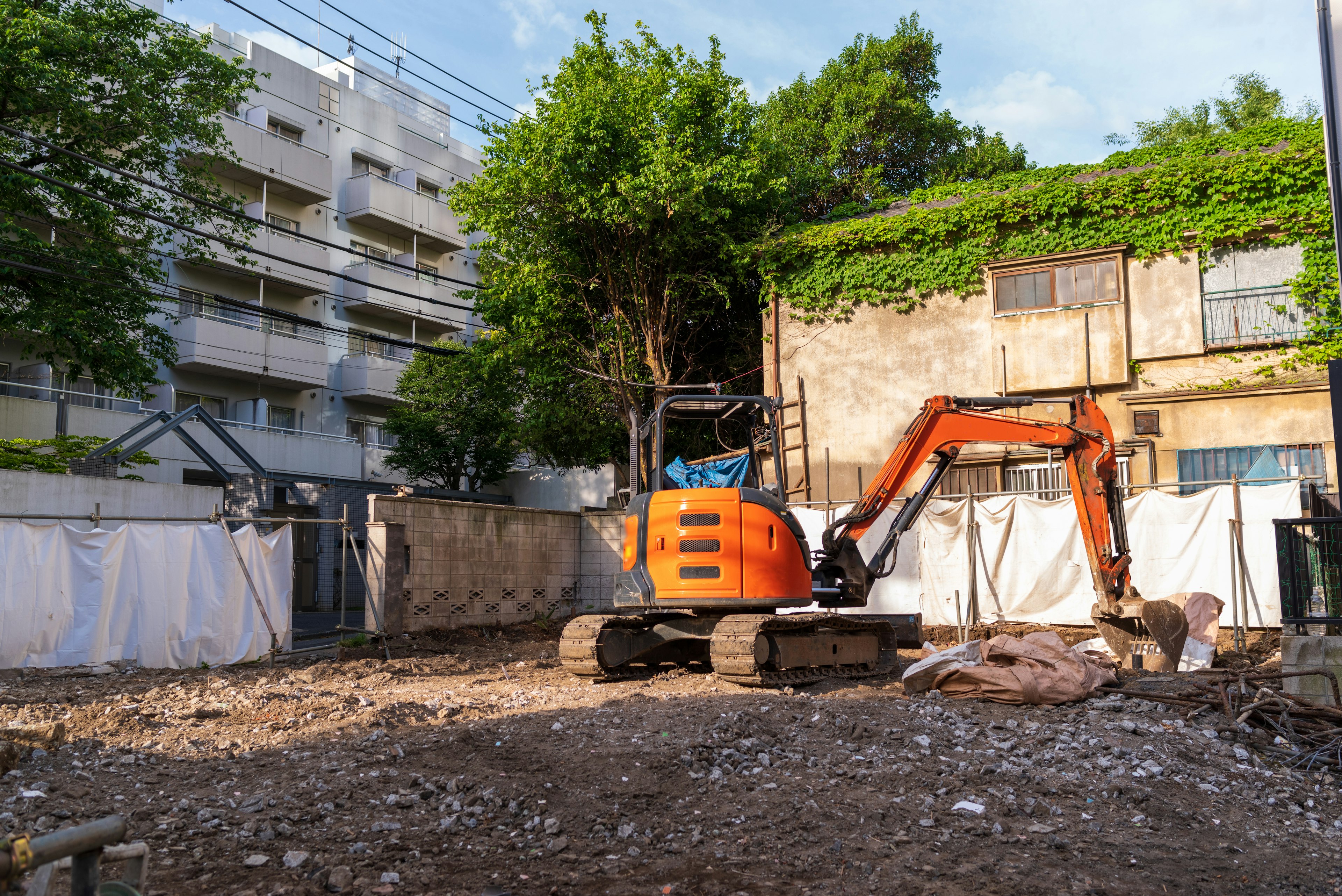 Bauplatz mit Bagger und Grünpflanzen