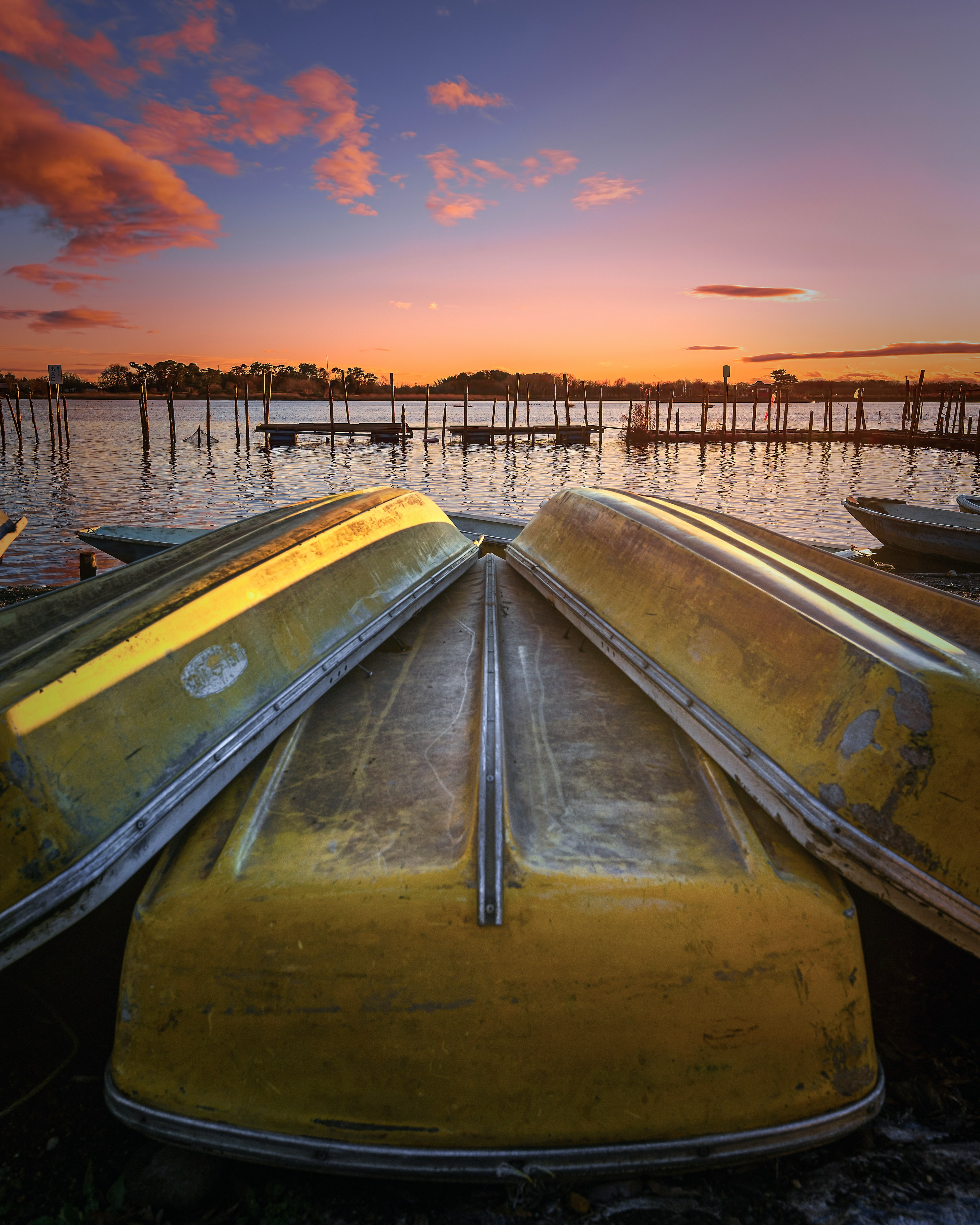 Hermoso paisaje con botes amarillos apilados bajo un atardecer