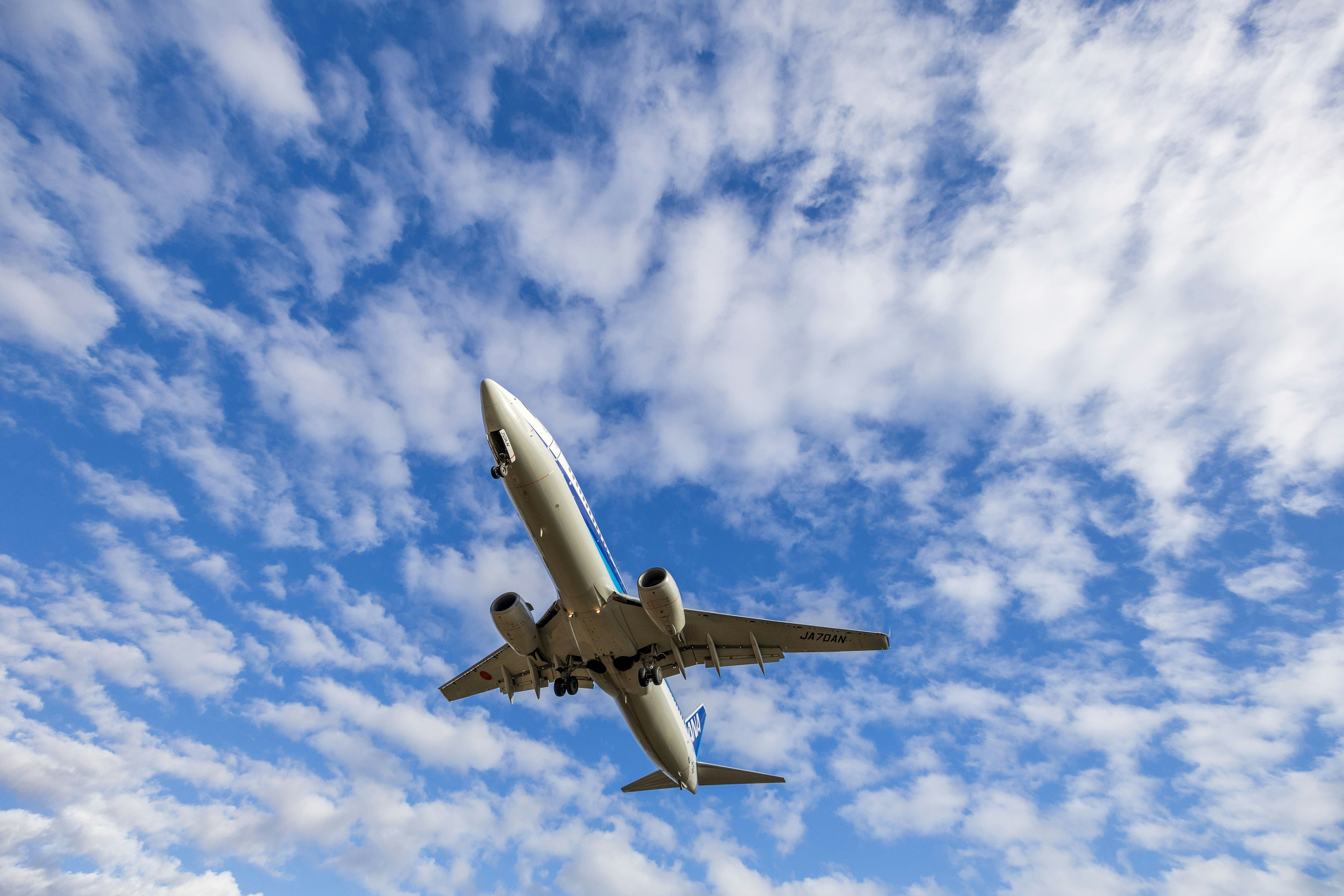 Ein Flugzeug fliegt gegen einen blauen Himmel mit Wolken