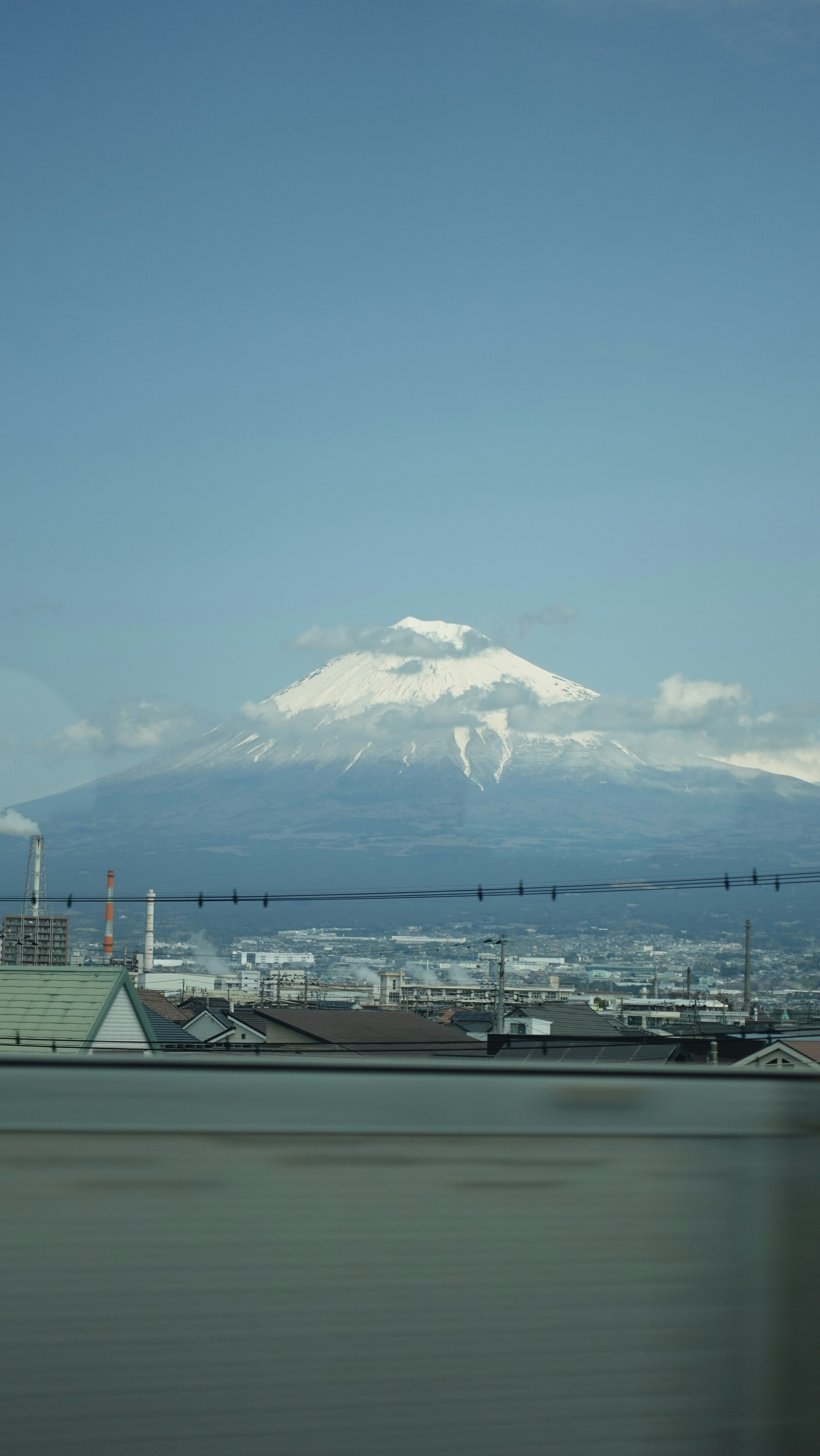 Snow-capped mountain under blue sky with urban landscape