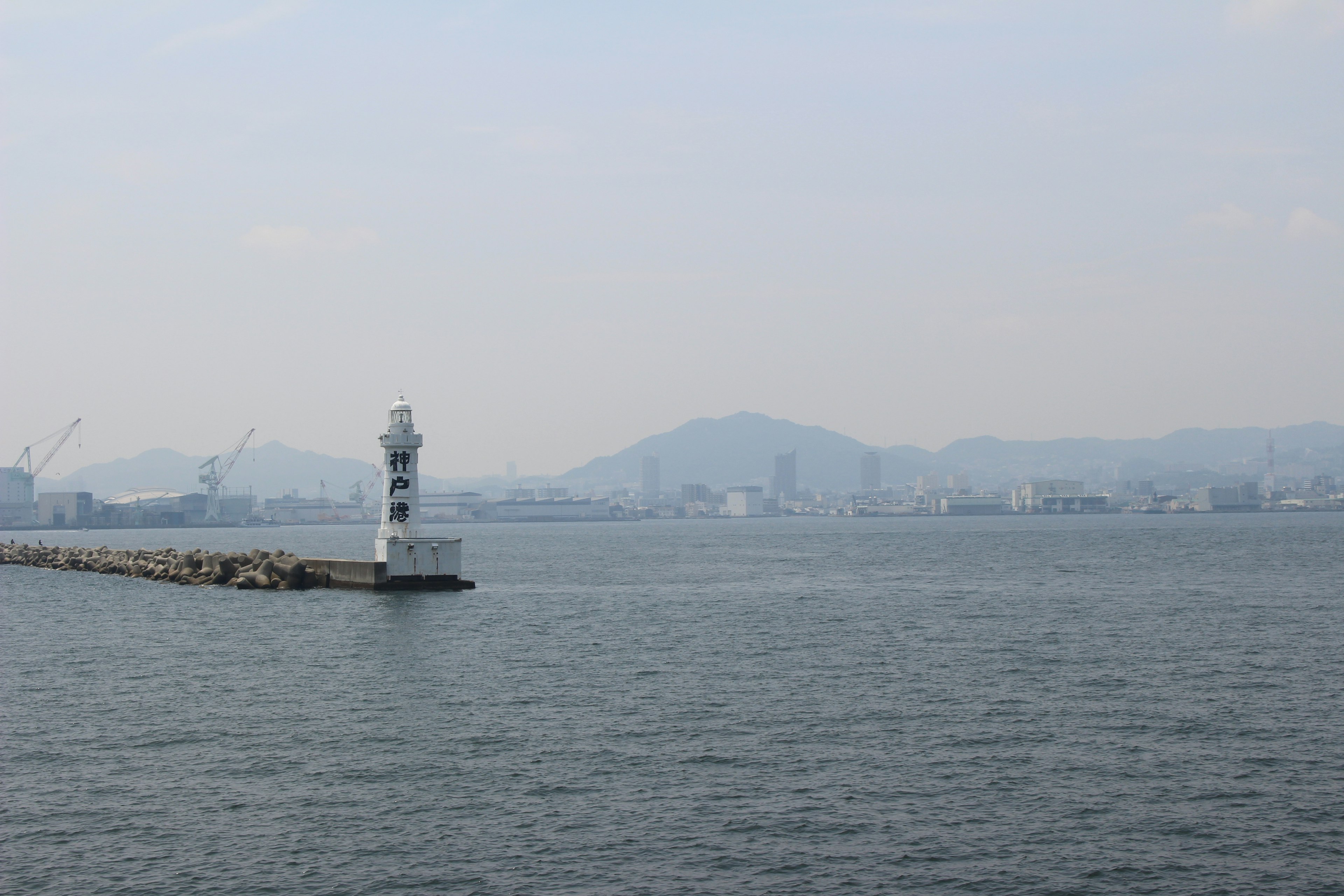 View of a lighthouse on the shore with distant mountains