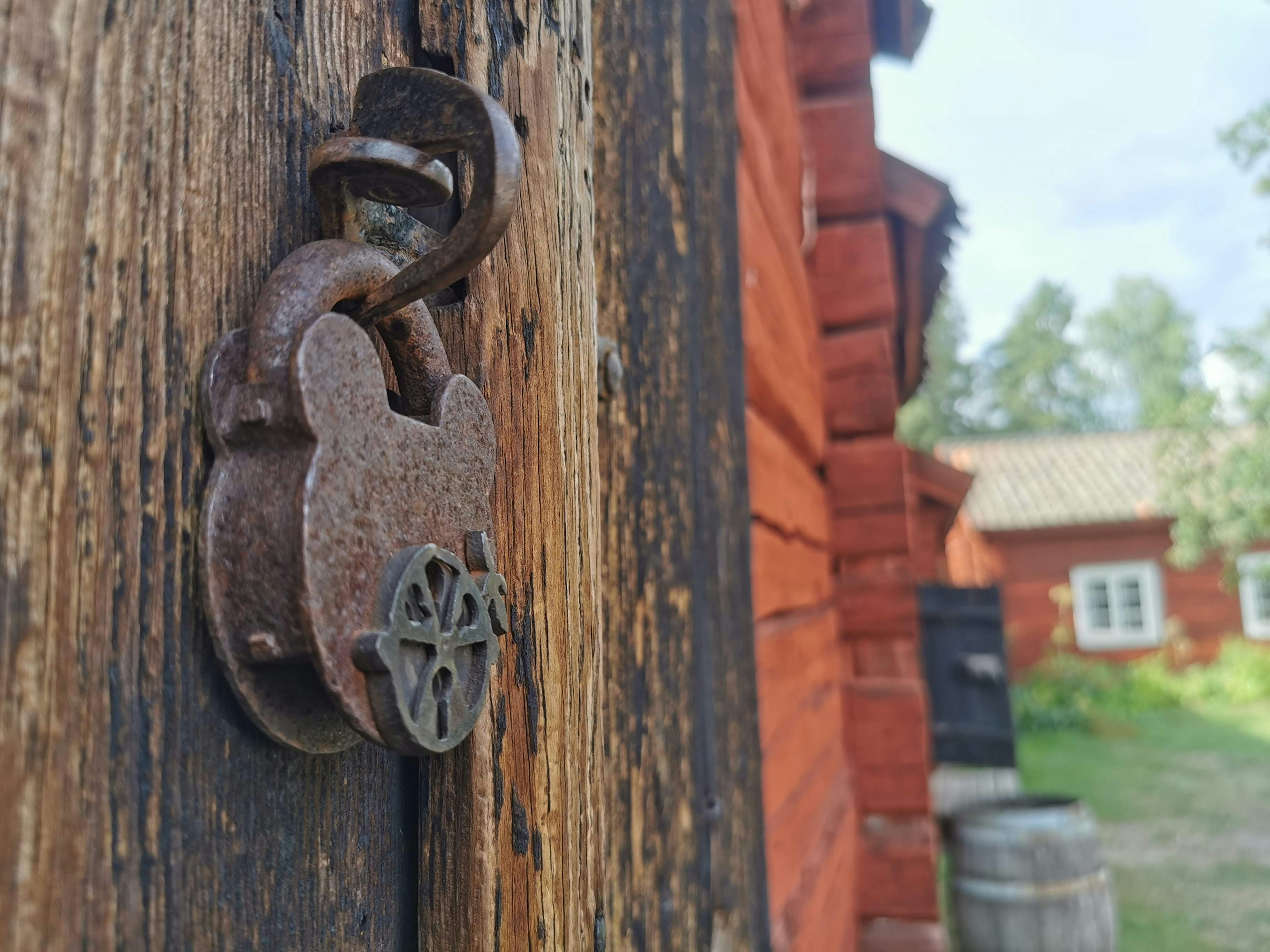 Rostiger Metallvorhängeschloss an einer alten Holztür befestigt