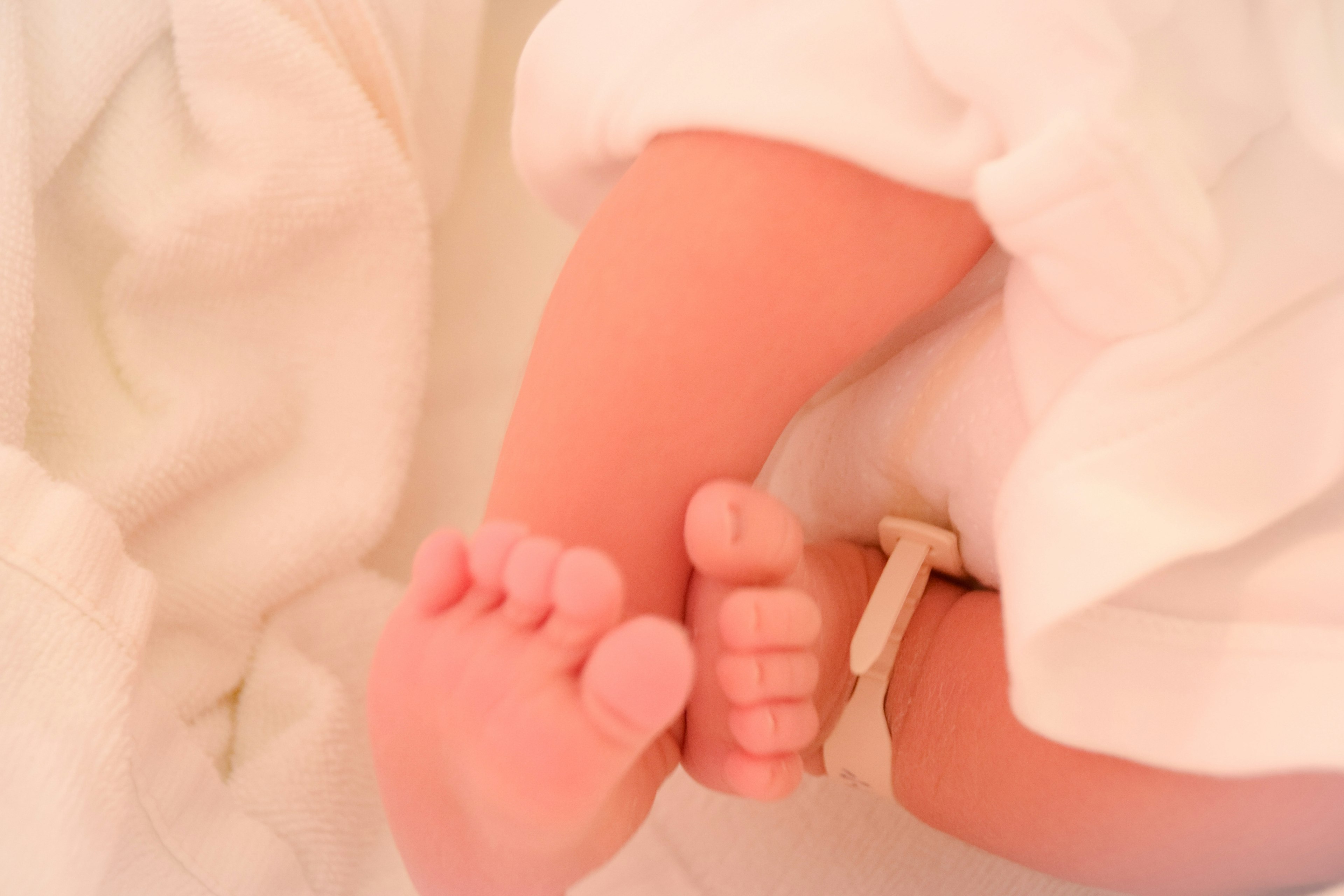 Piedi e caviglie di un bambino appoggiati su un morbido tessuto bianco