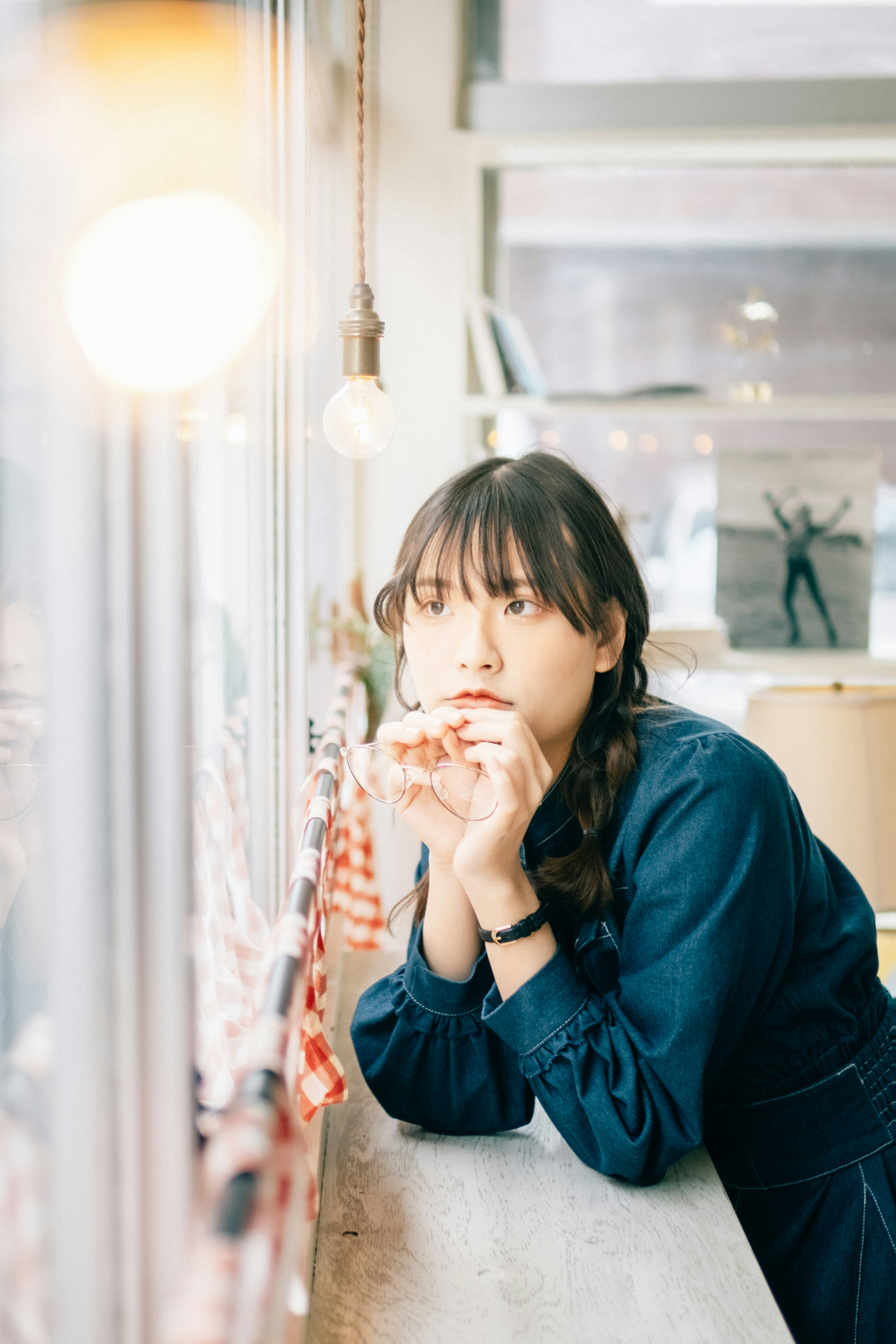 A woman sitting by the cafe window appears pensive