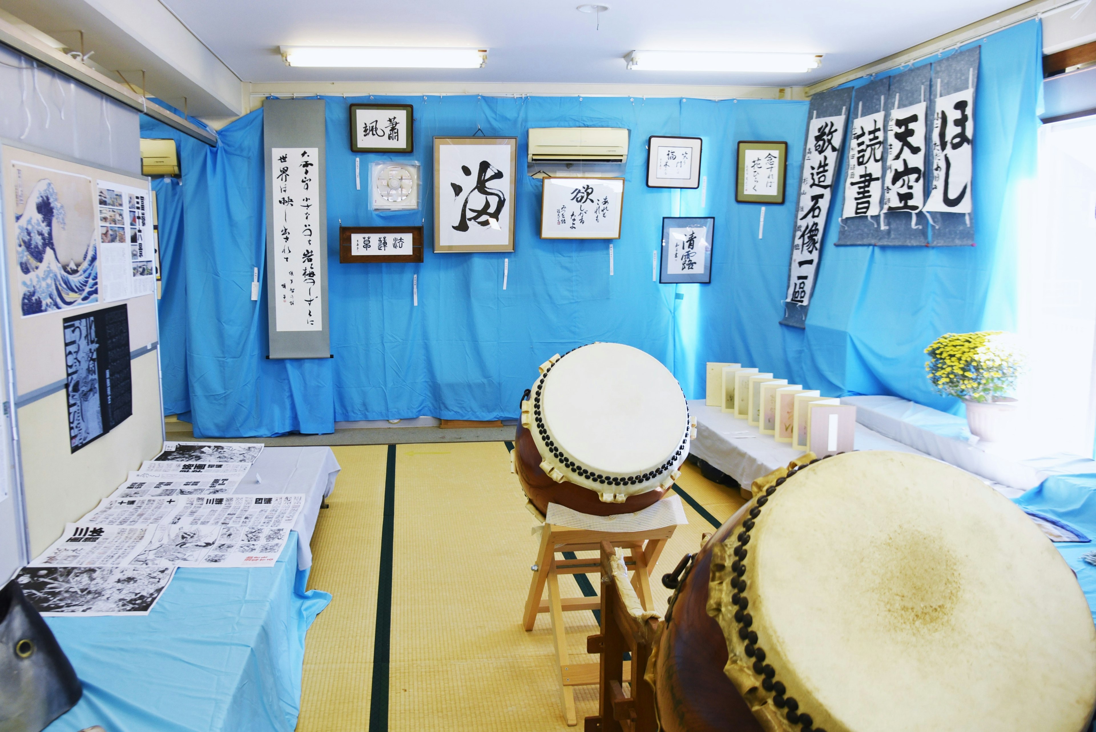 Espace artistique avec des tambours taiko et des œuvres de calligraphie sur fond bleu