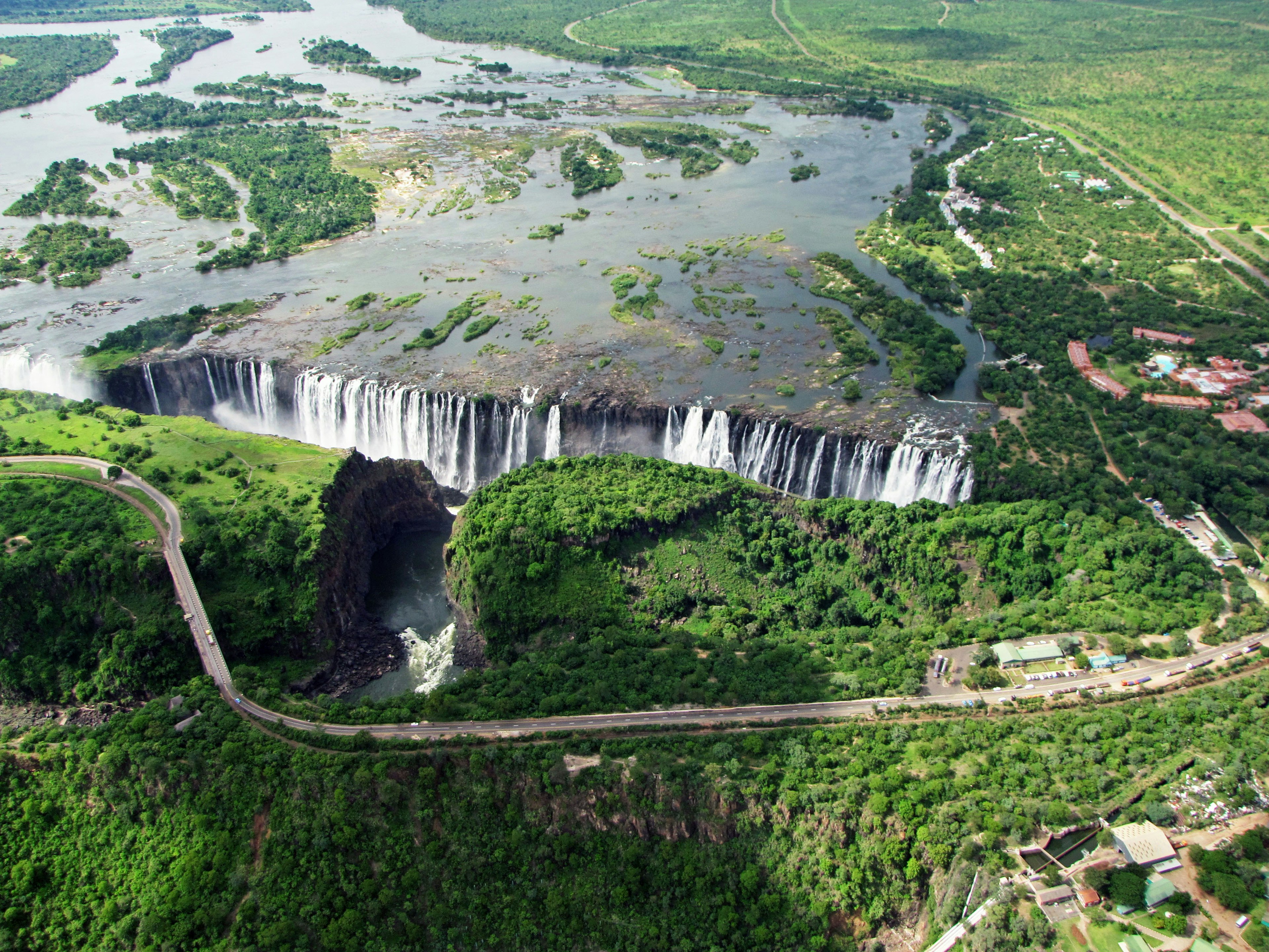 Luftaufnahme eines majestätischen Wasserfalls umgeben von üppigem Grün und Wasserflächen